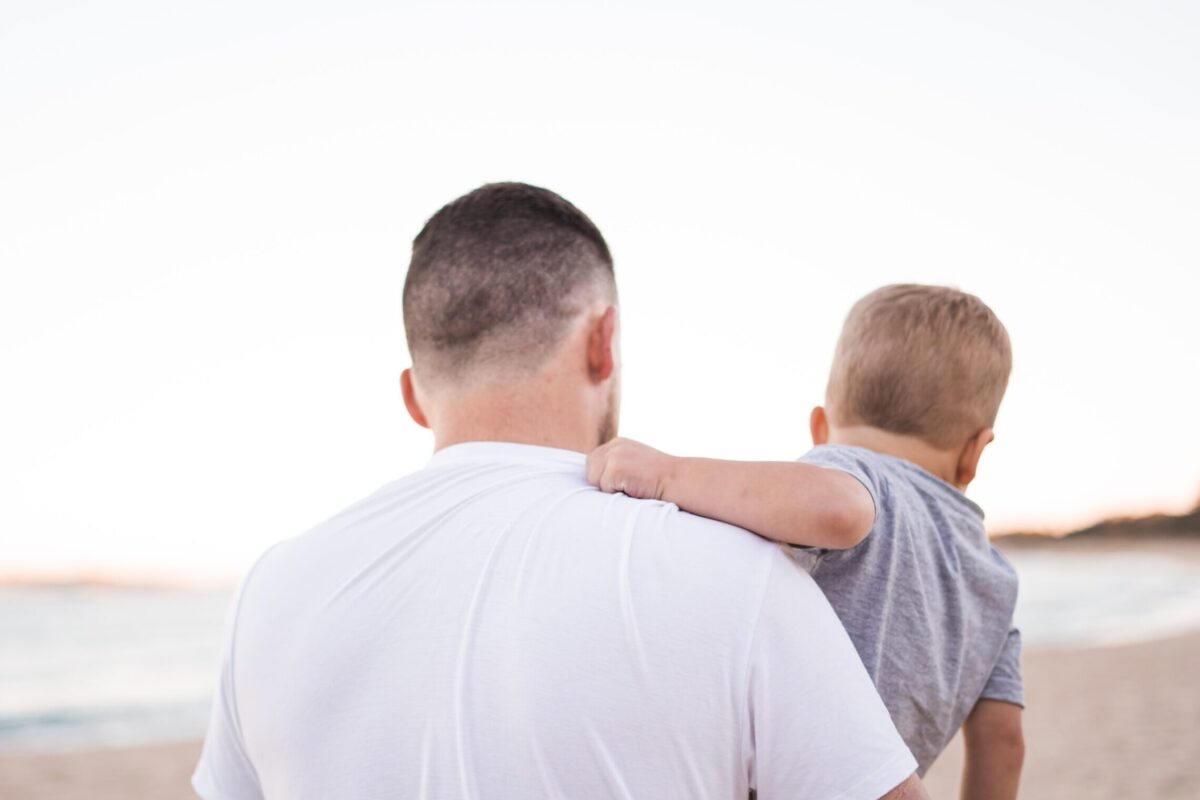 man carrying baby near the ocean