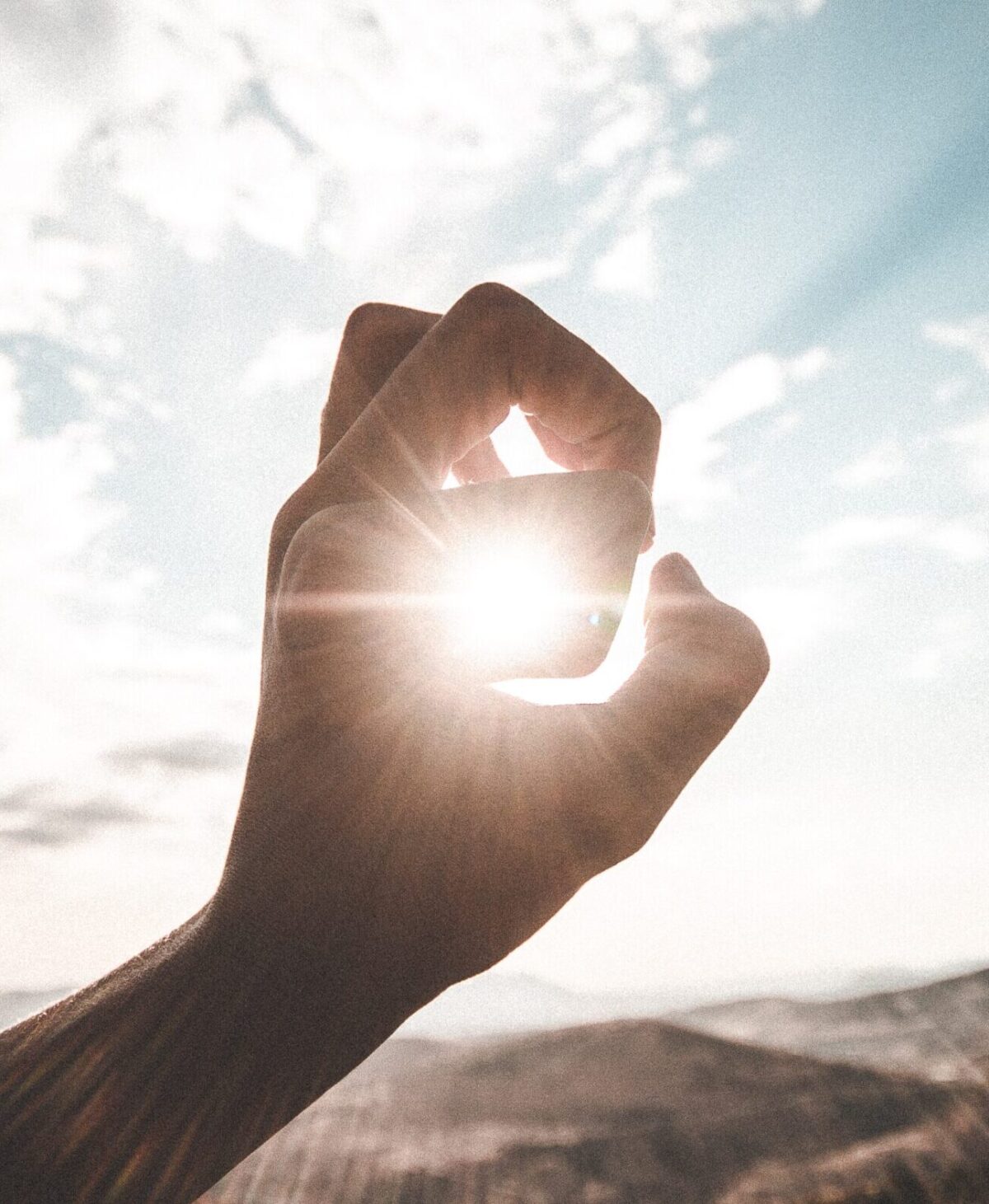 photography of sun glaring through the hole of finger