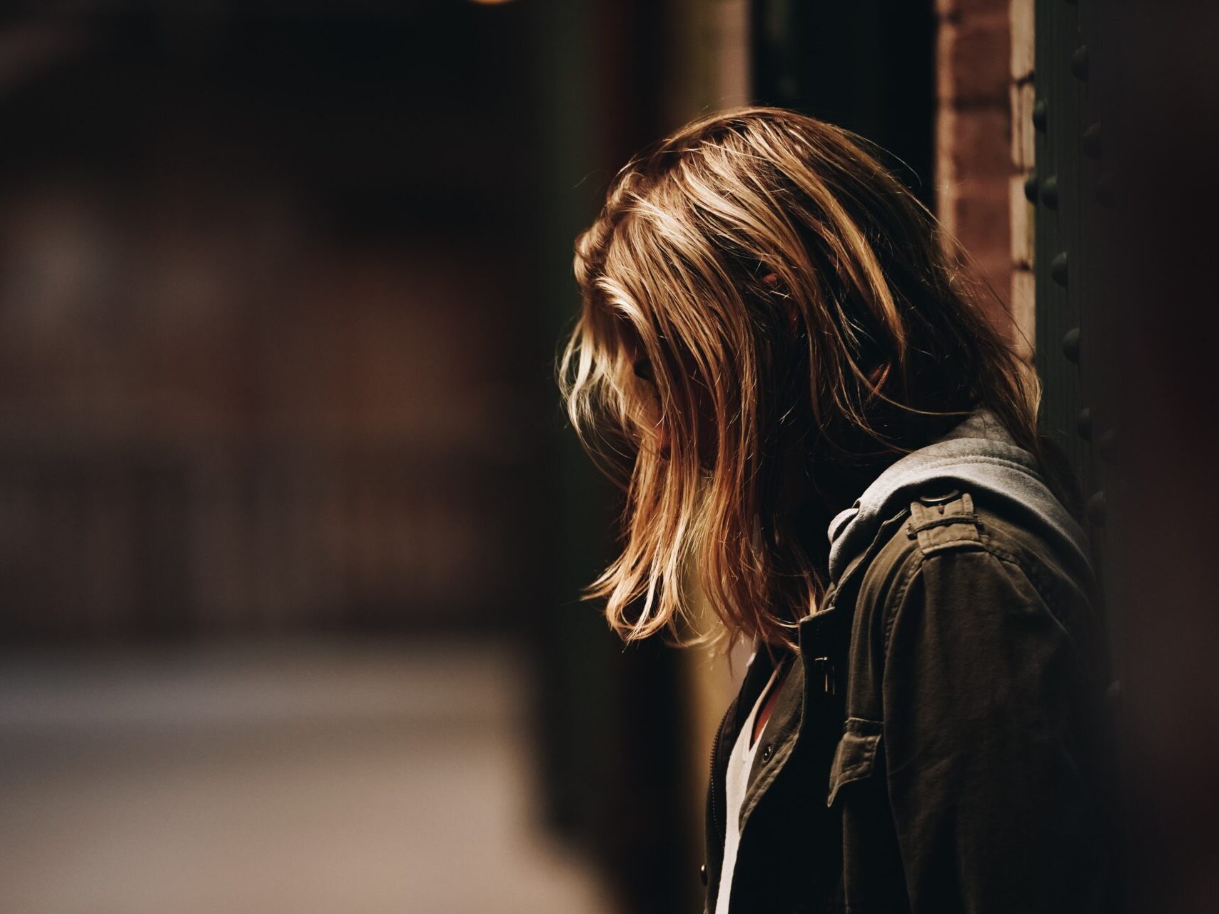 woman leaning against a wall in dim hallway