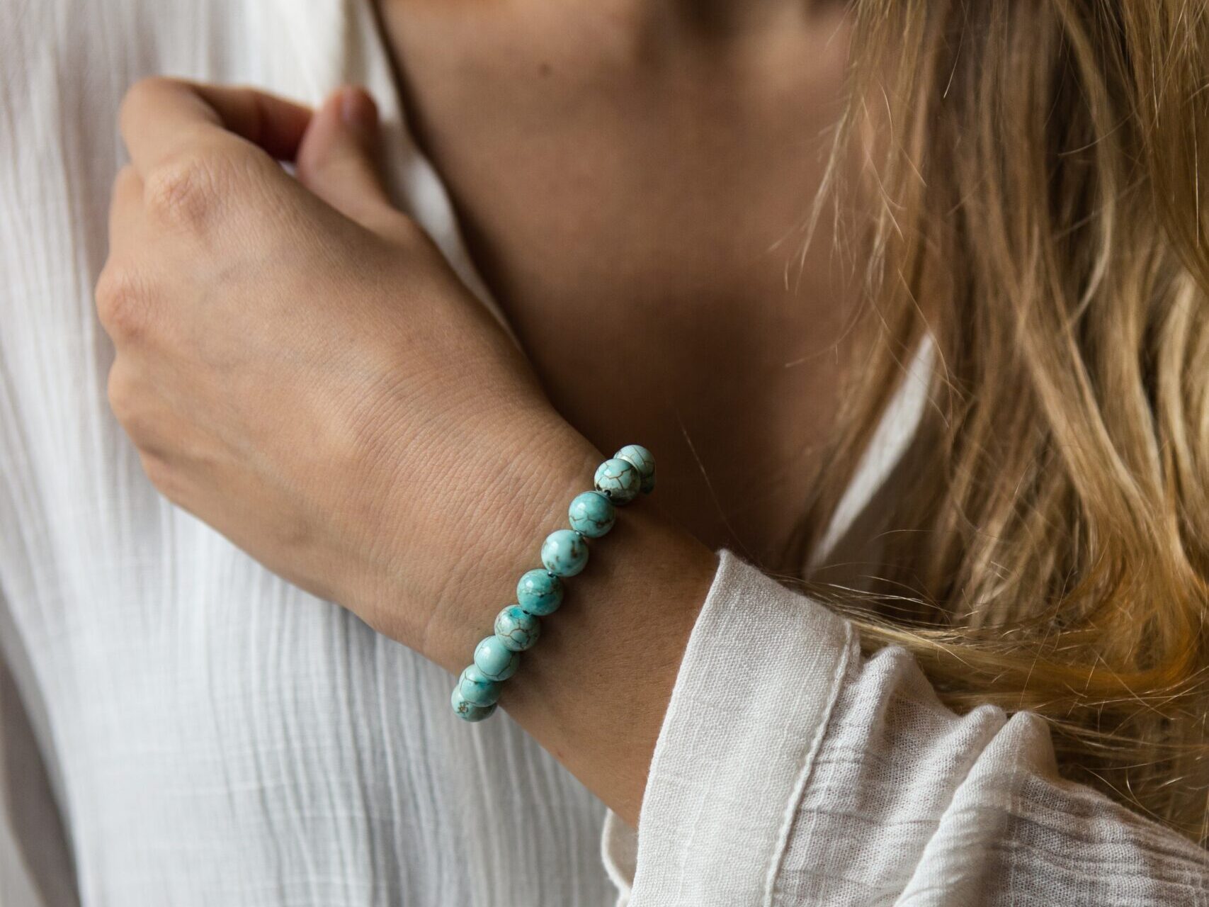 woman in white long sleeve shirt wearing silver and green beaded bracelet