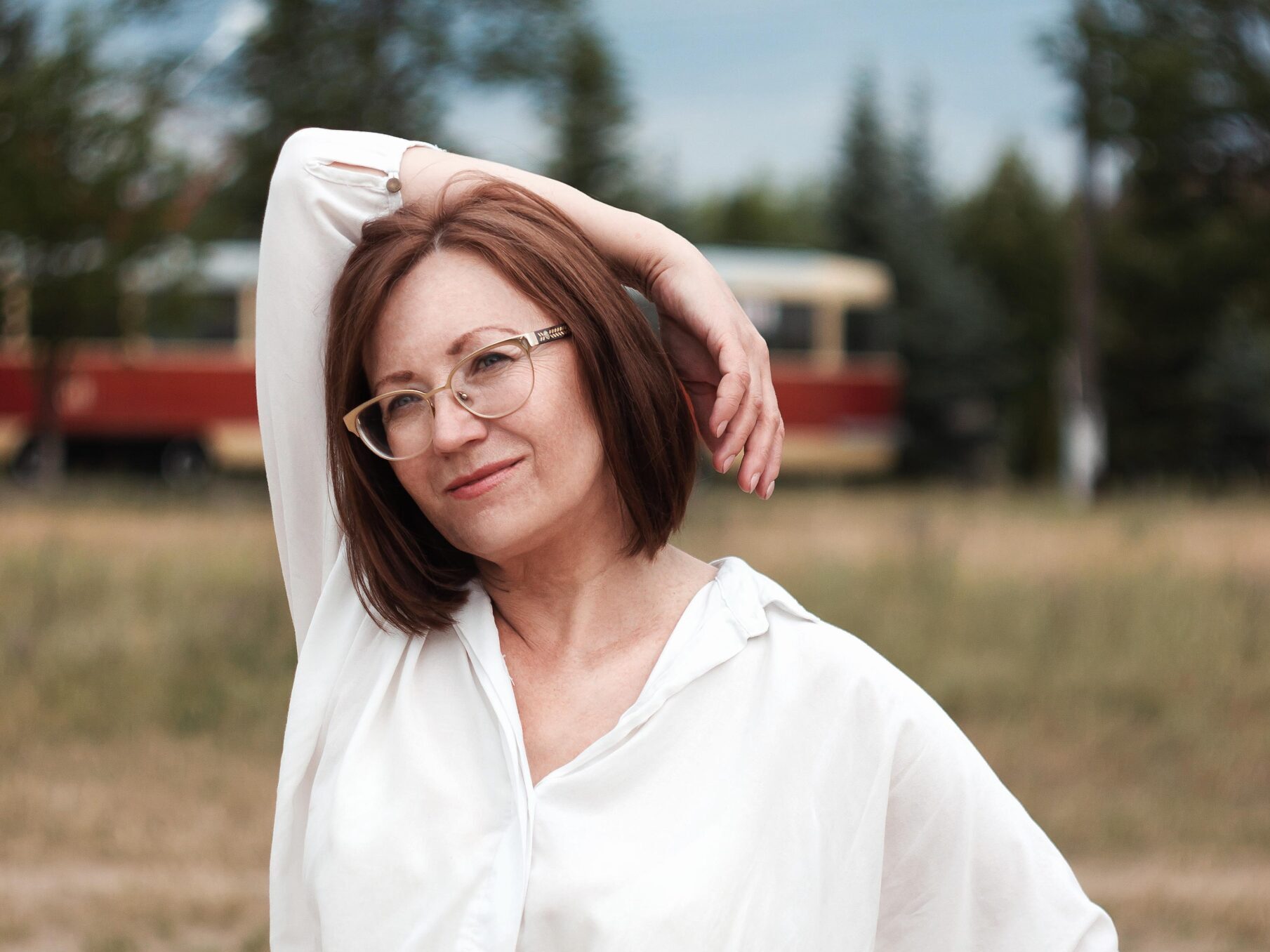 woman in white button up shirt and blue skirt standing on brown sand during daytime