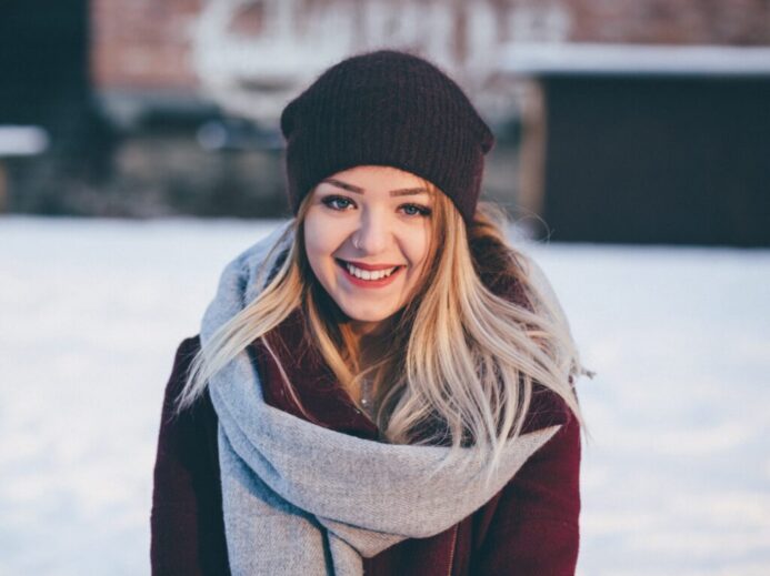 smiling woman wearing brown scarf and maroon coat on snow field