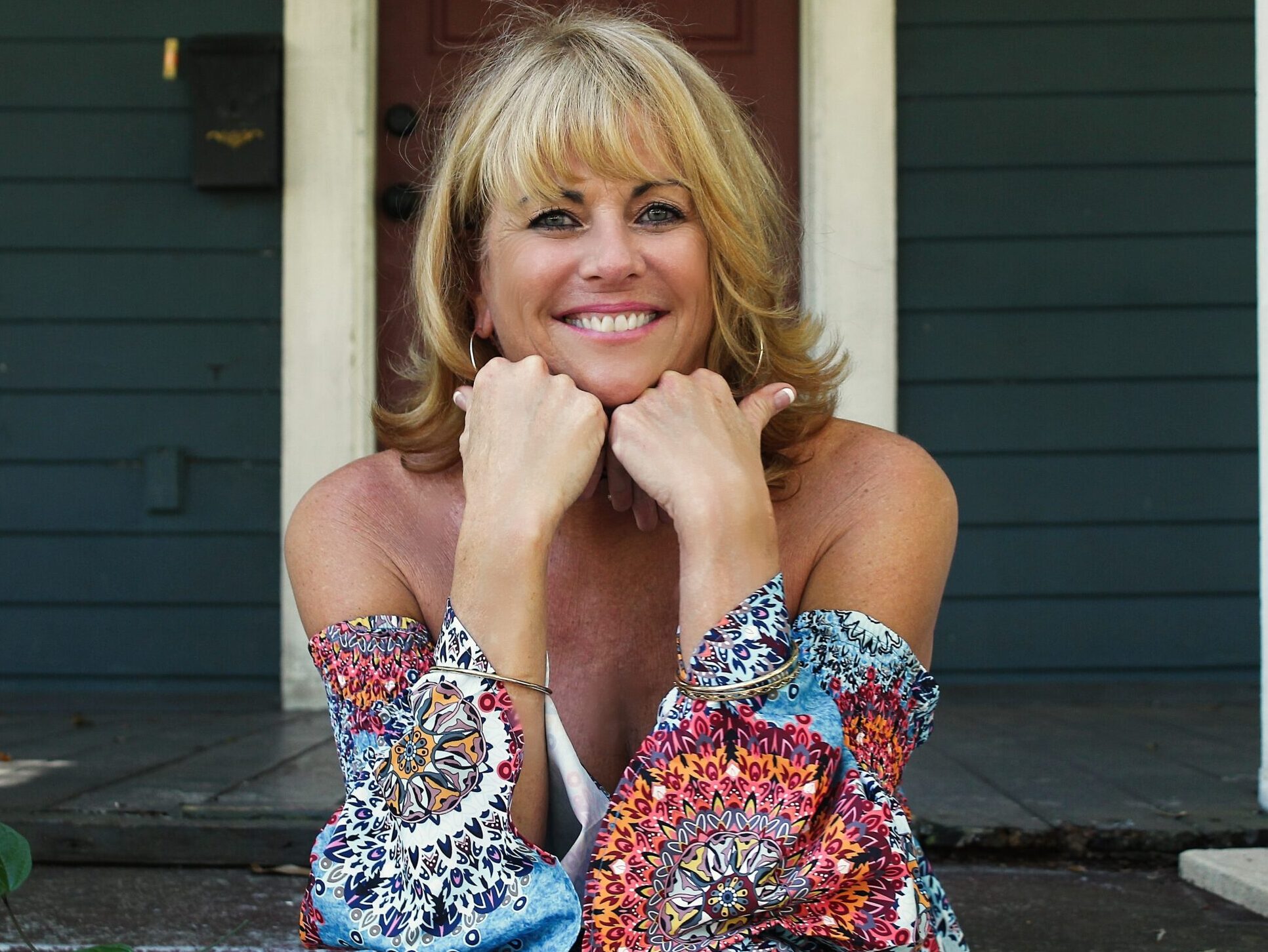 woman in blue white and red floral dress sitting on stairs
