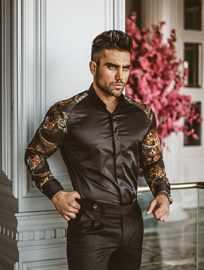 man in black leather jacket standing near white wall