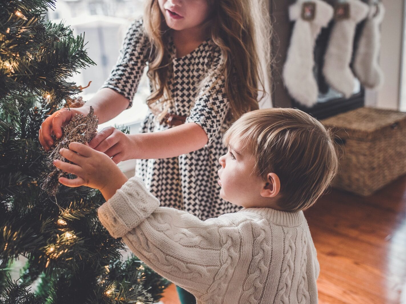 boy and girl decorating Christmas tree inside room
