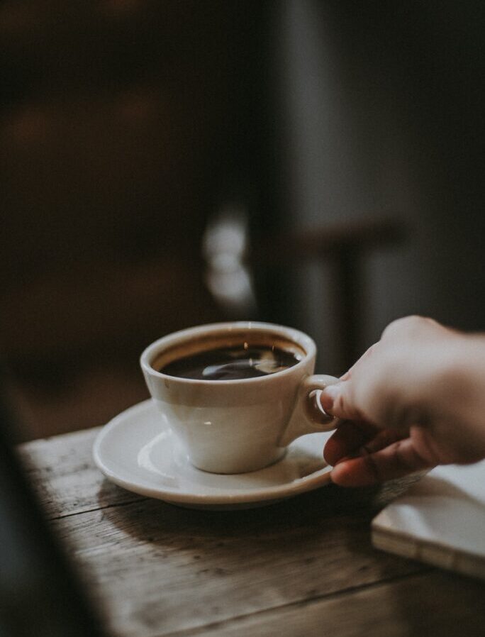 person holding white ceramic cup with liquid