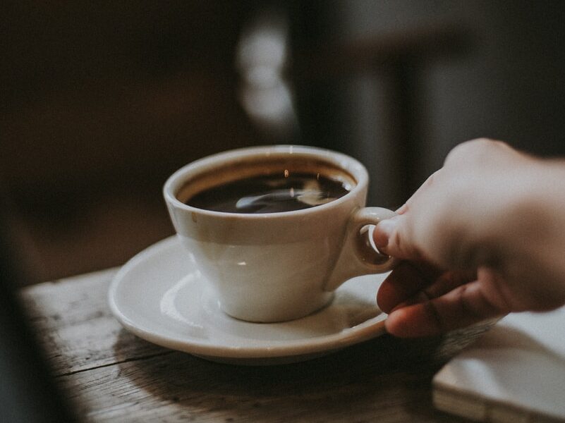 person holding white ceramic cup with liquid