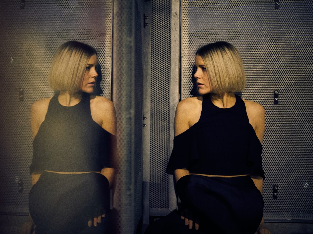 woman leaning on wall looking beside mirror