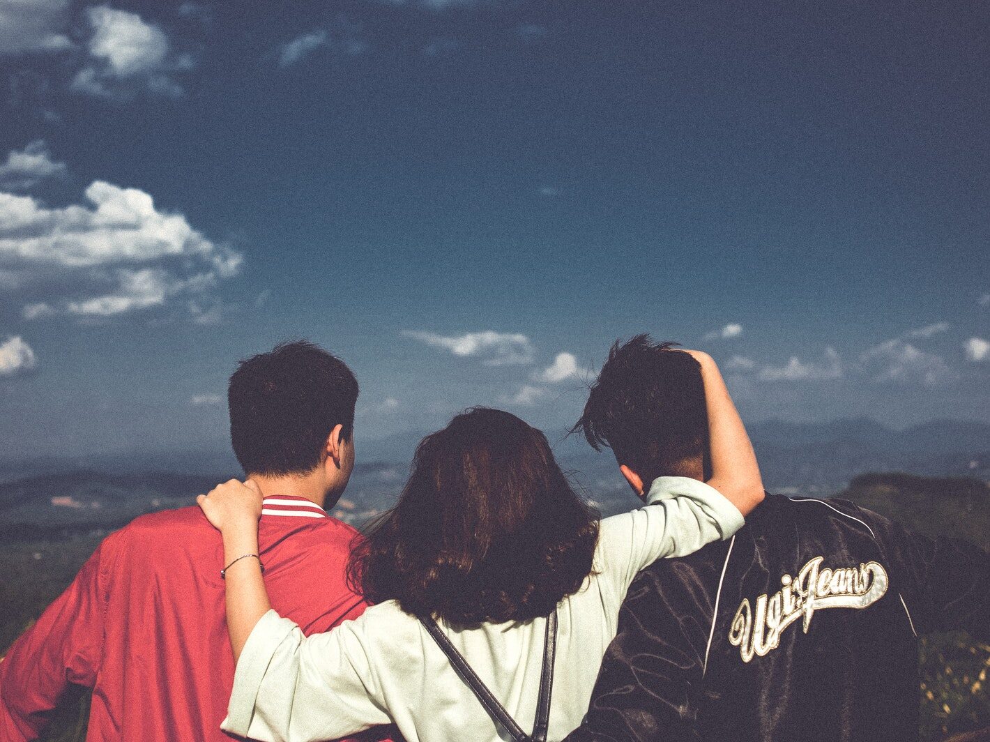 Woman Between Men Facing Mountains
