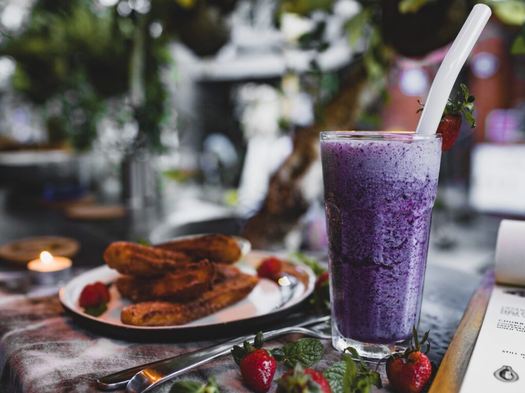 Delicious churros with fresh strawberries and blueberry smoothie in cafe