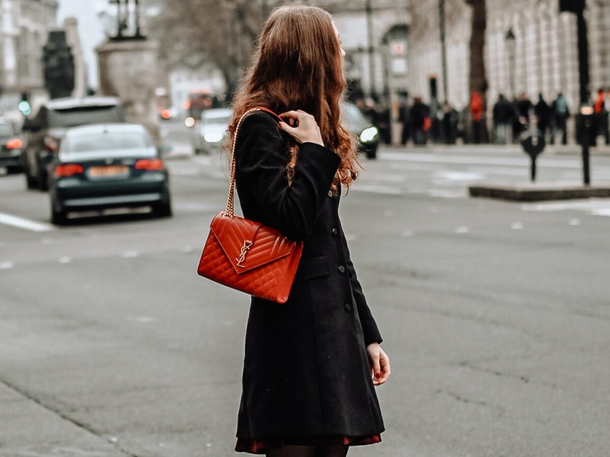 woman in black coat standing on sidewalk during daytime