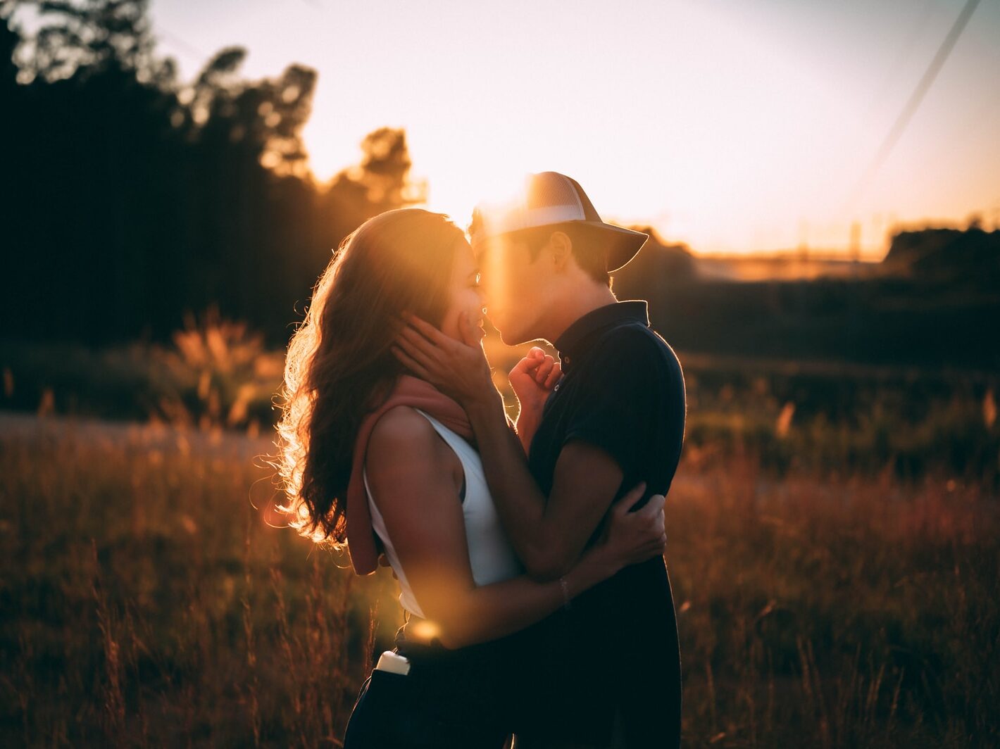 man and woman kissing during sunset