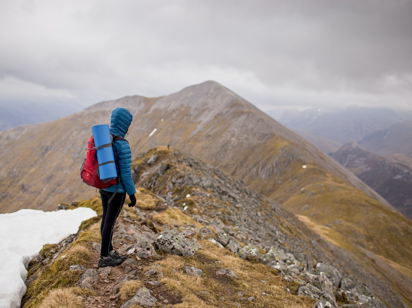 person at peak of mountain carrying red backpack