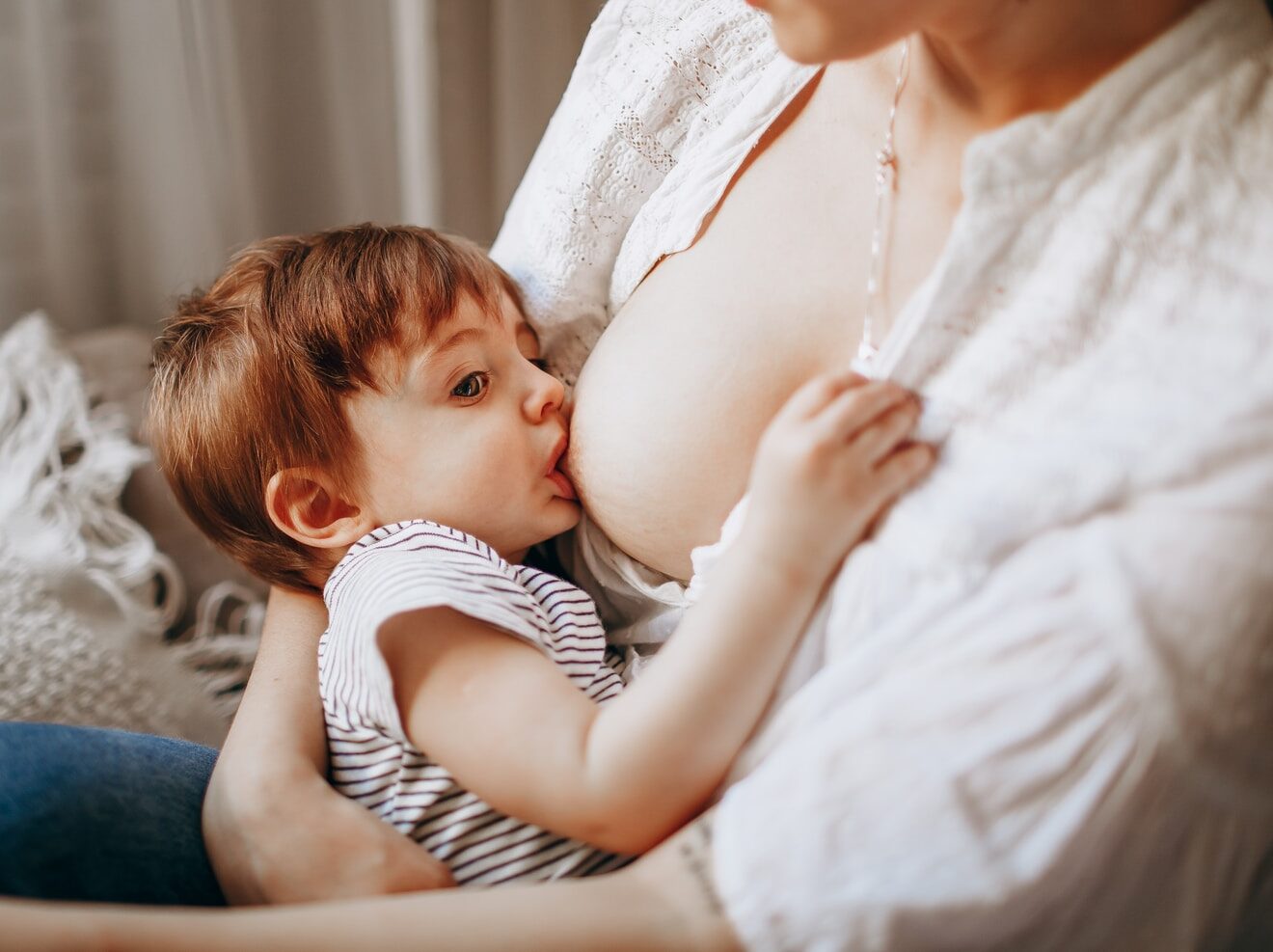 woman in white tank top carrying baby in black and white stripe onesie