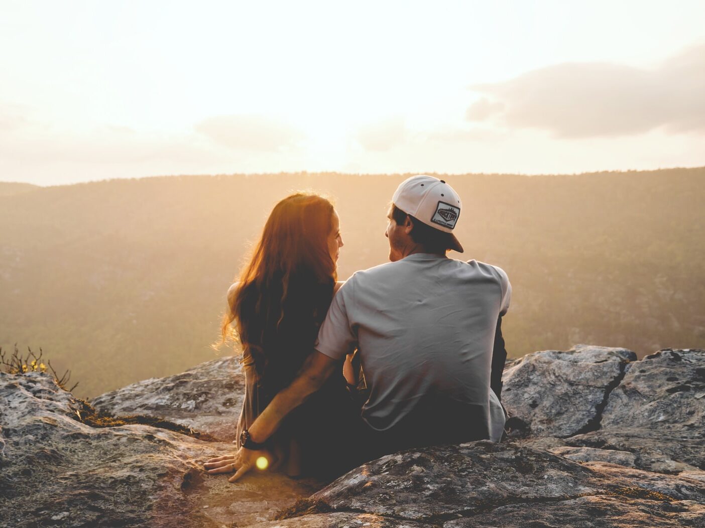 man and woman sitting on rock during daytime