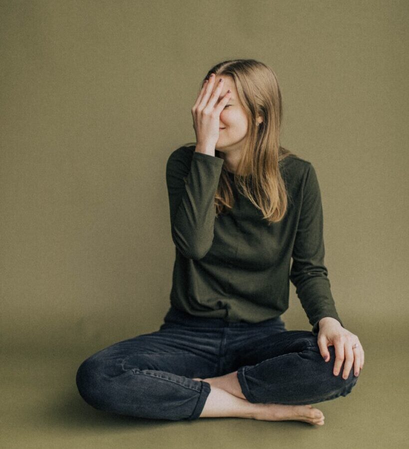 woman in black long sleeve shirt and blue denim jeans sitting on brown wooden chair