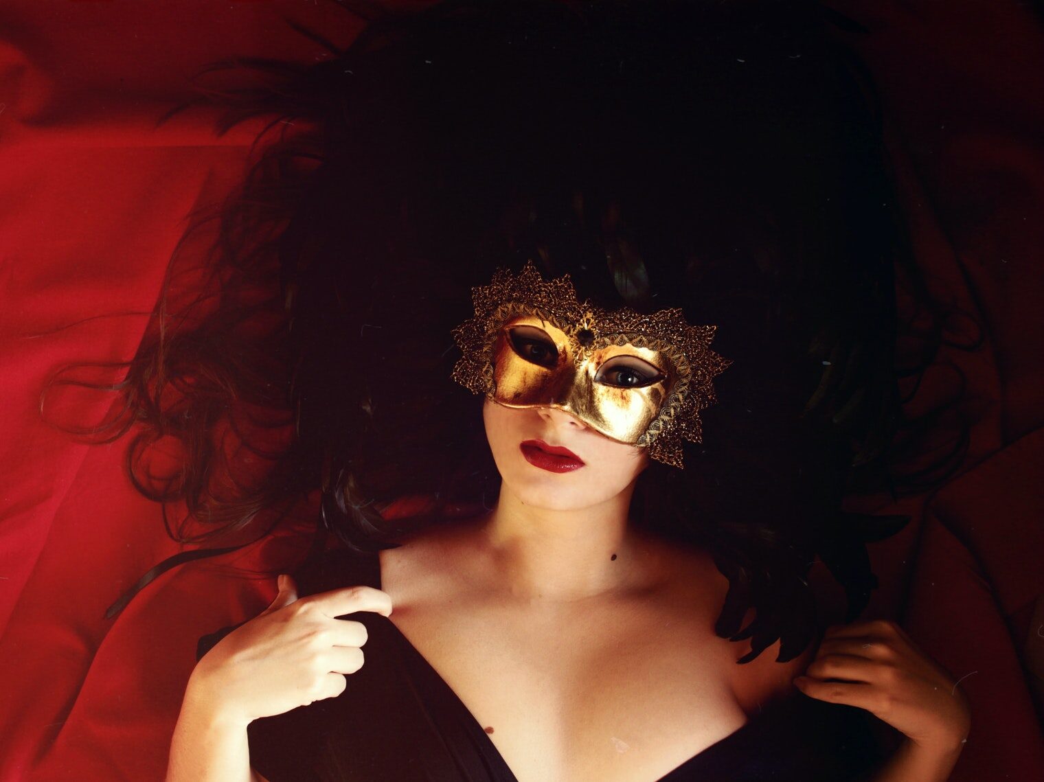 Woman Laying On Red Textile Wearing Gold Mask
