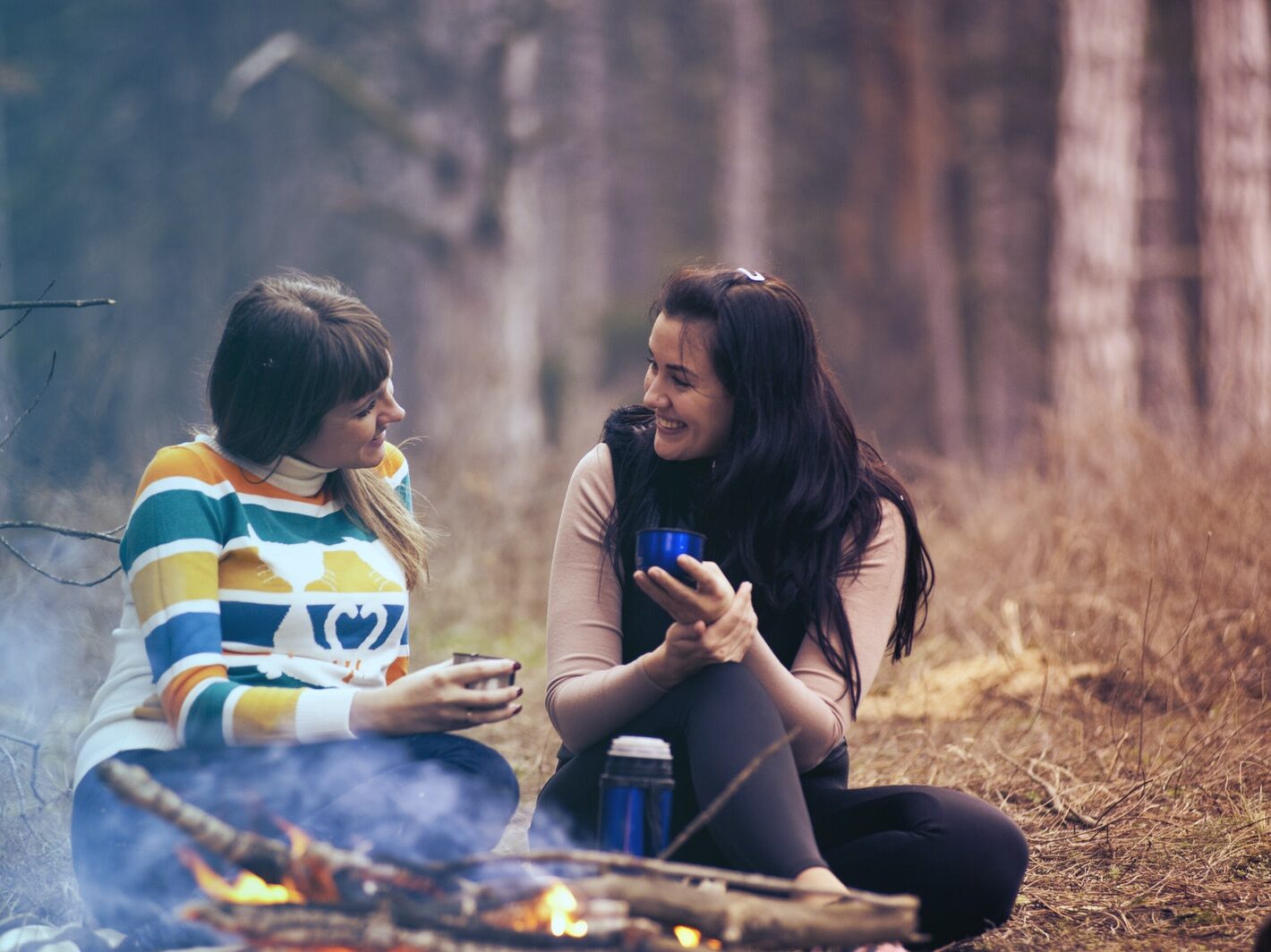 Two Women Sitting on Ground Near Bonfire