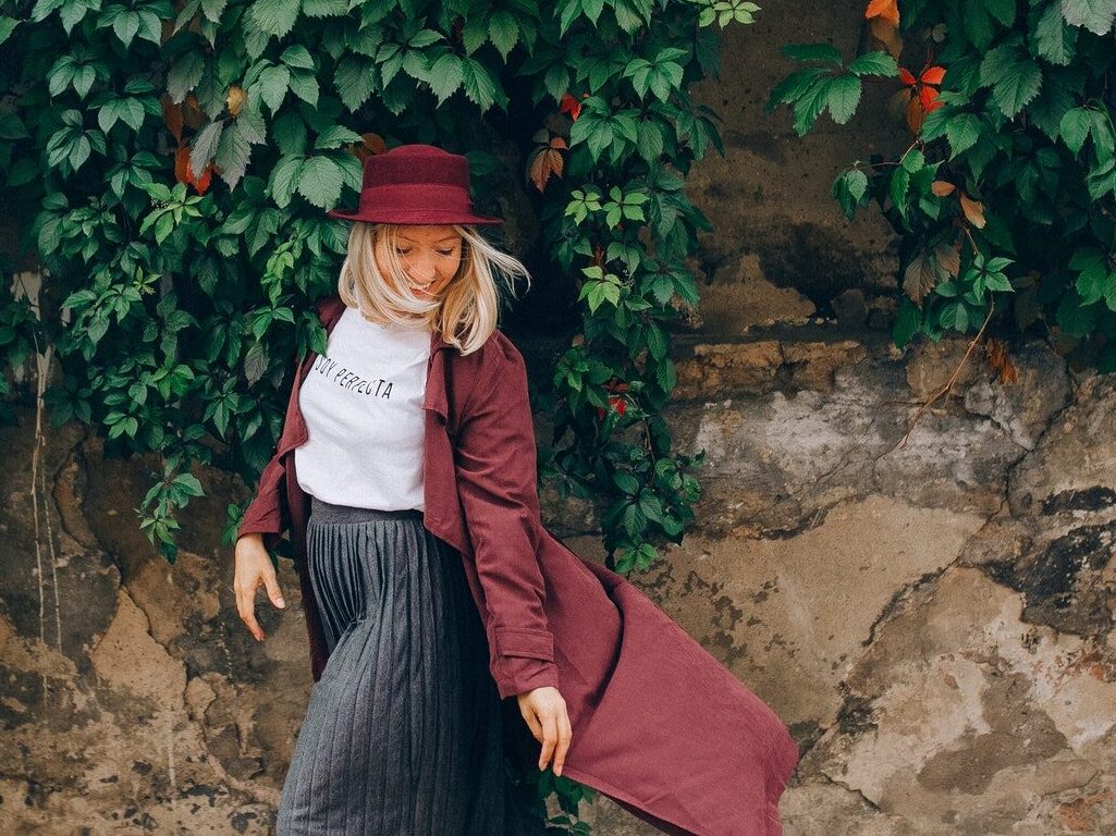 Woman in Red Coat and Black Skirt Sitting on Brown Rock