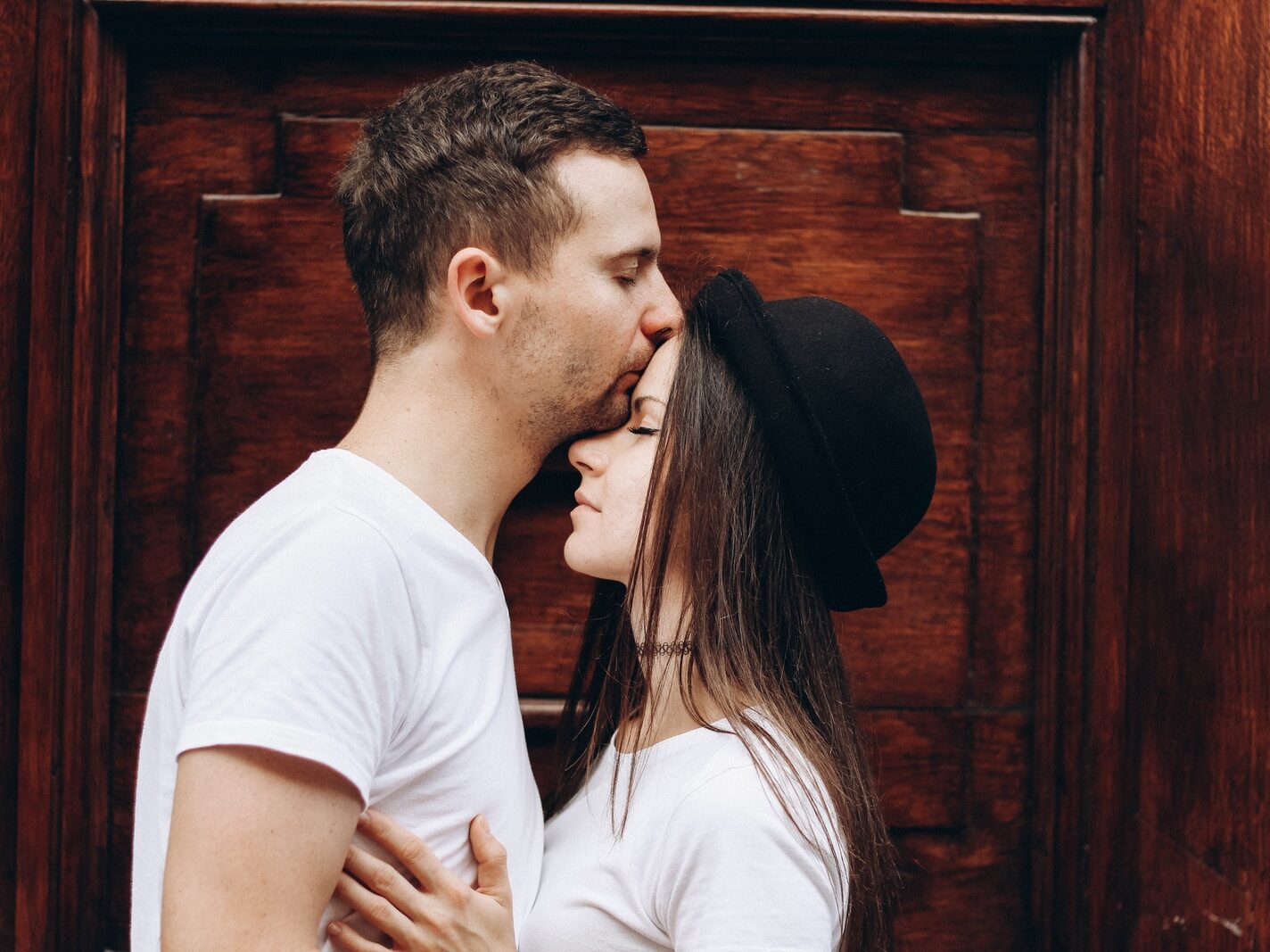 man kissing woman forehead