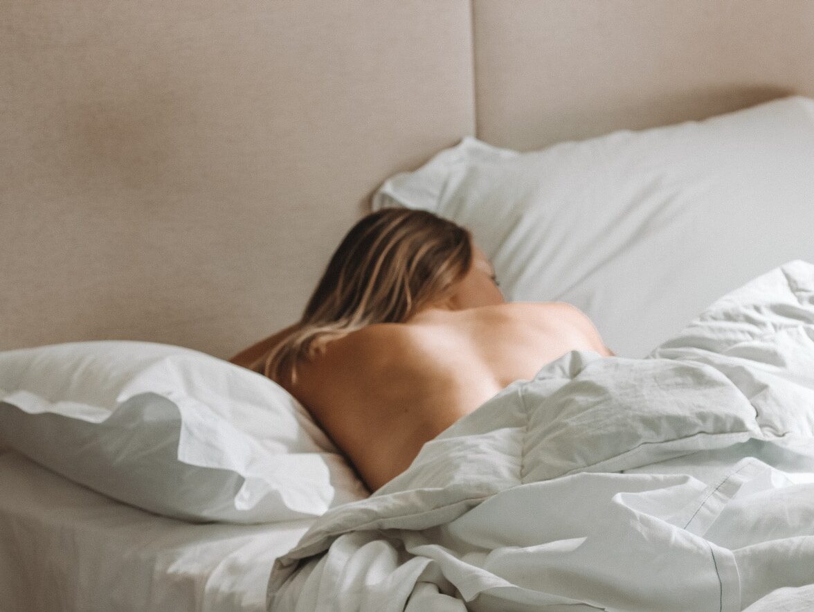 naked woman lying on bed during daytime