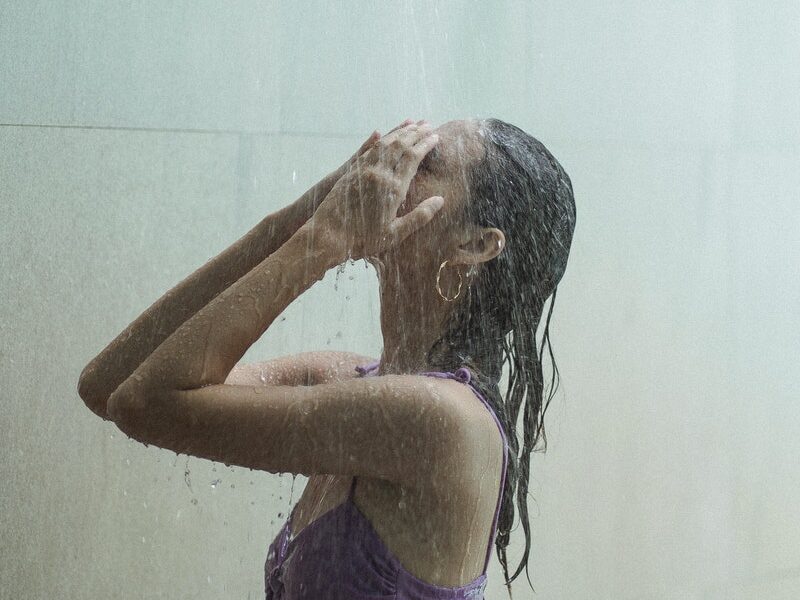 Sensual woman in bikini under stream in shower