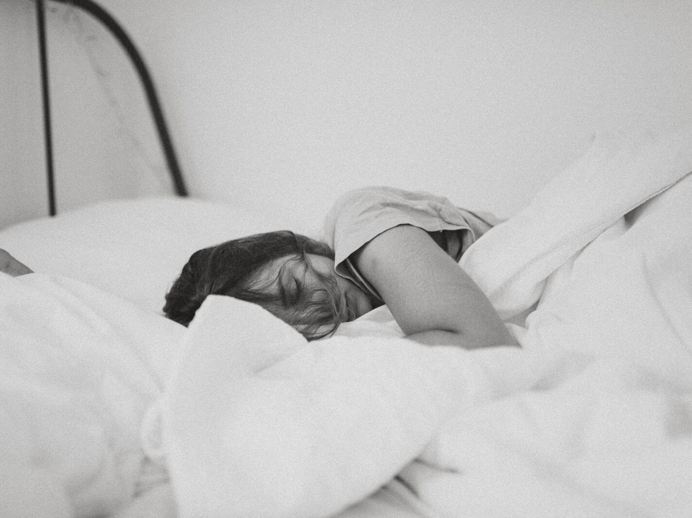 grayscale photo of sleeping woman lying on bed