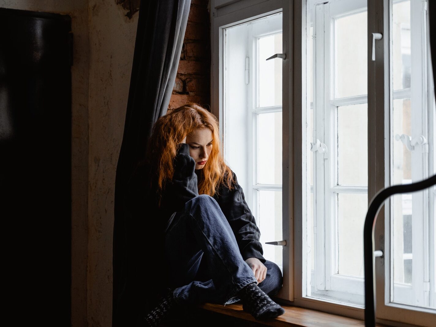 Woman in Black Leather Jacket Sitting on Brown Wooden Floor