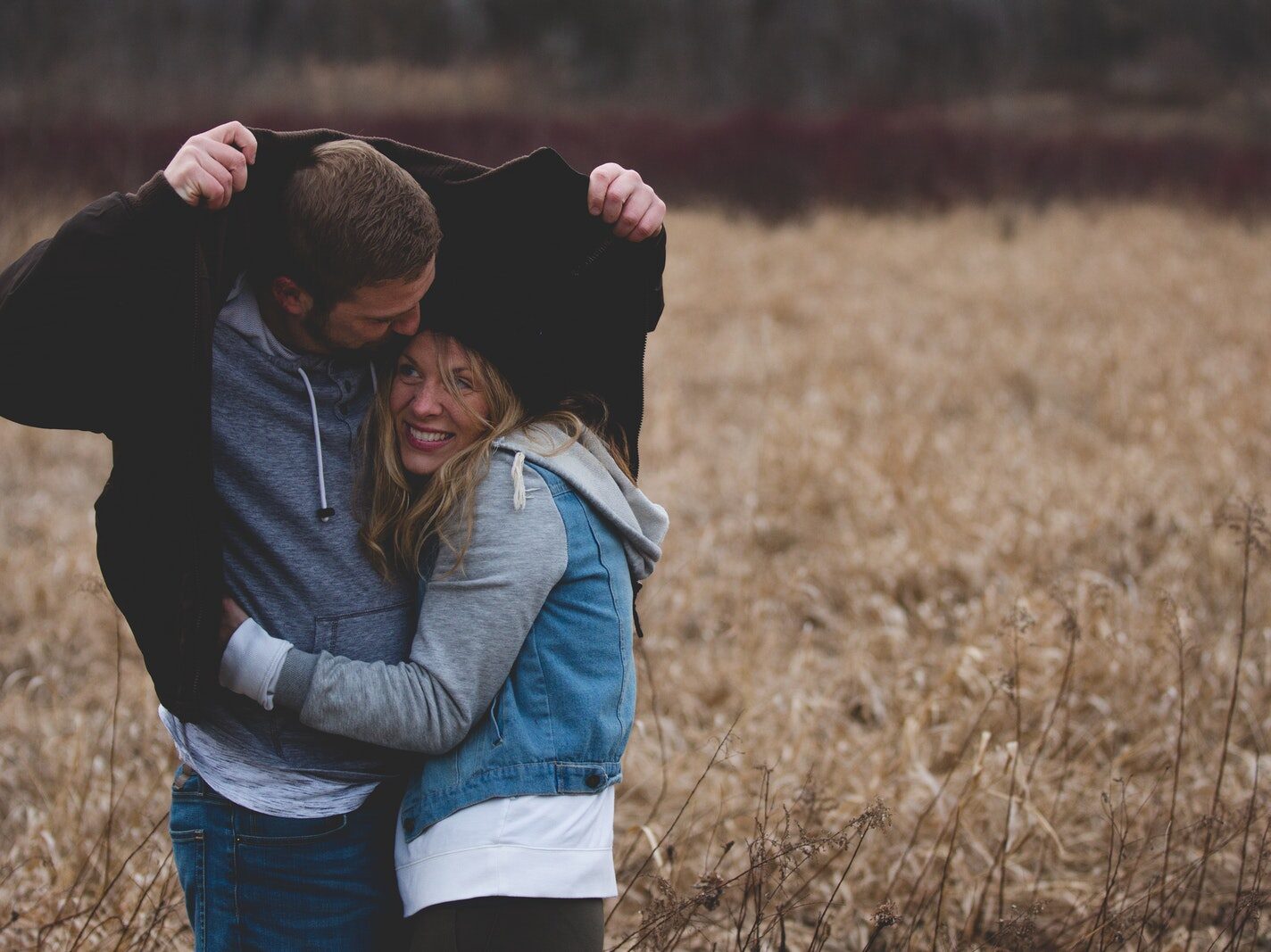 Man and Woman Hugging on Brown Field