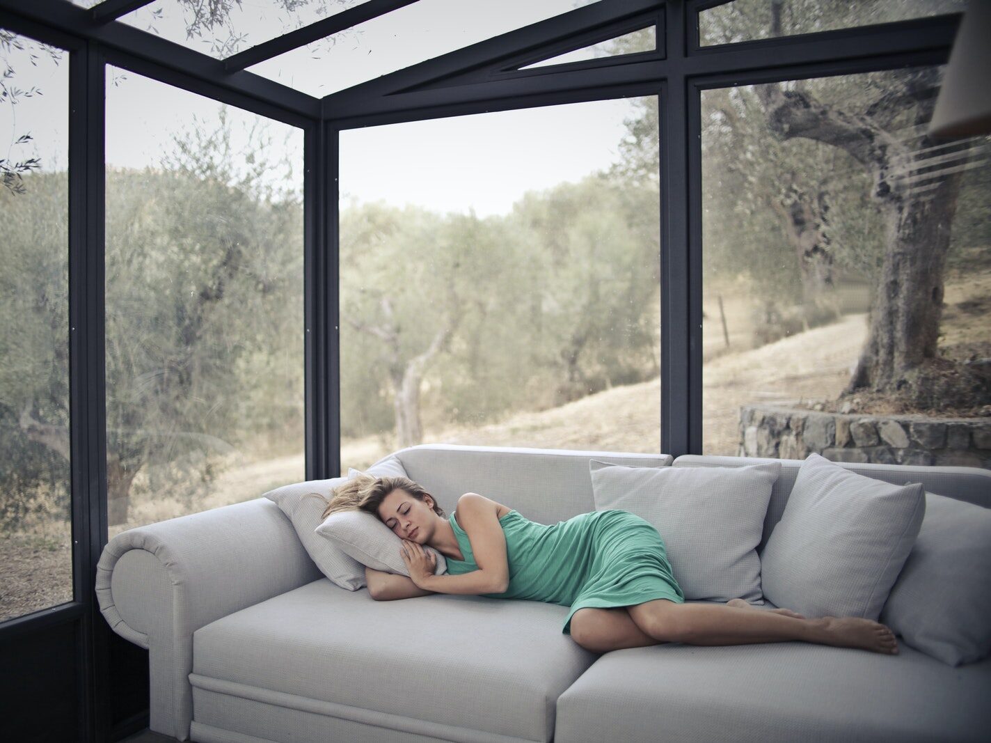 Woman Sleeping On Sofa With Throw Pillows