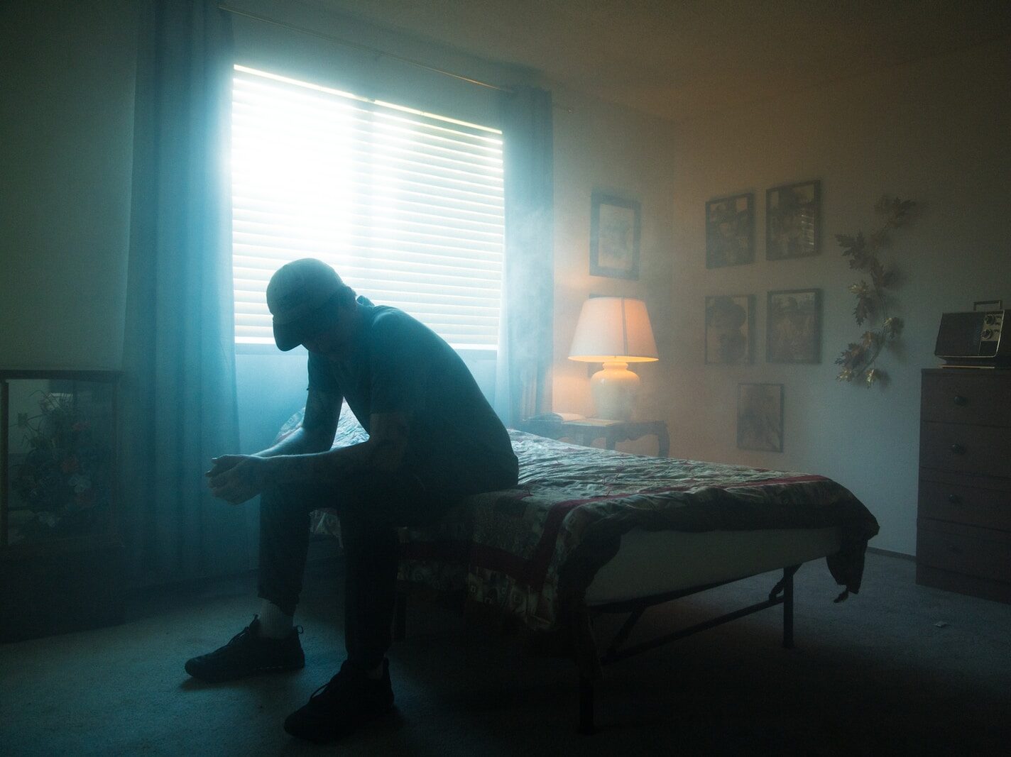 man in black jacket sitting on bed