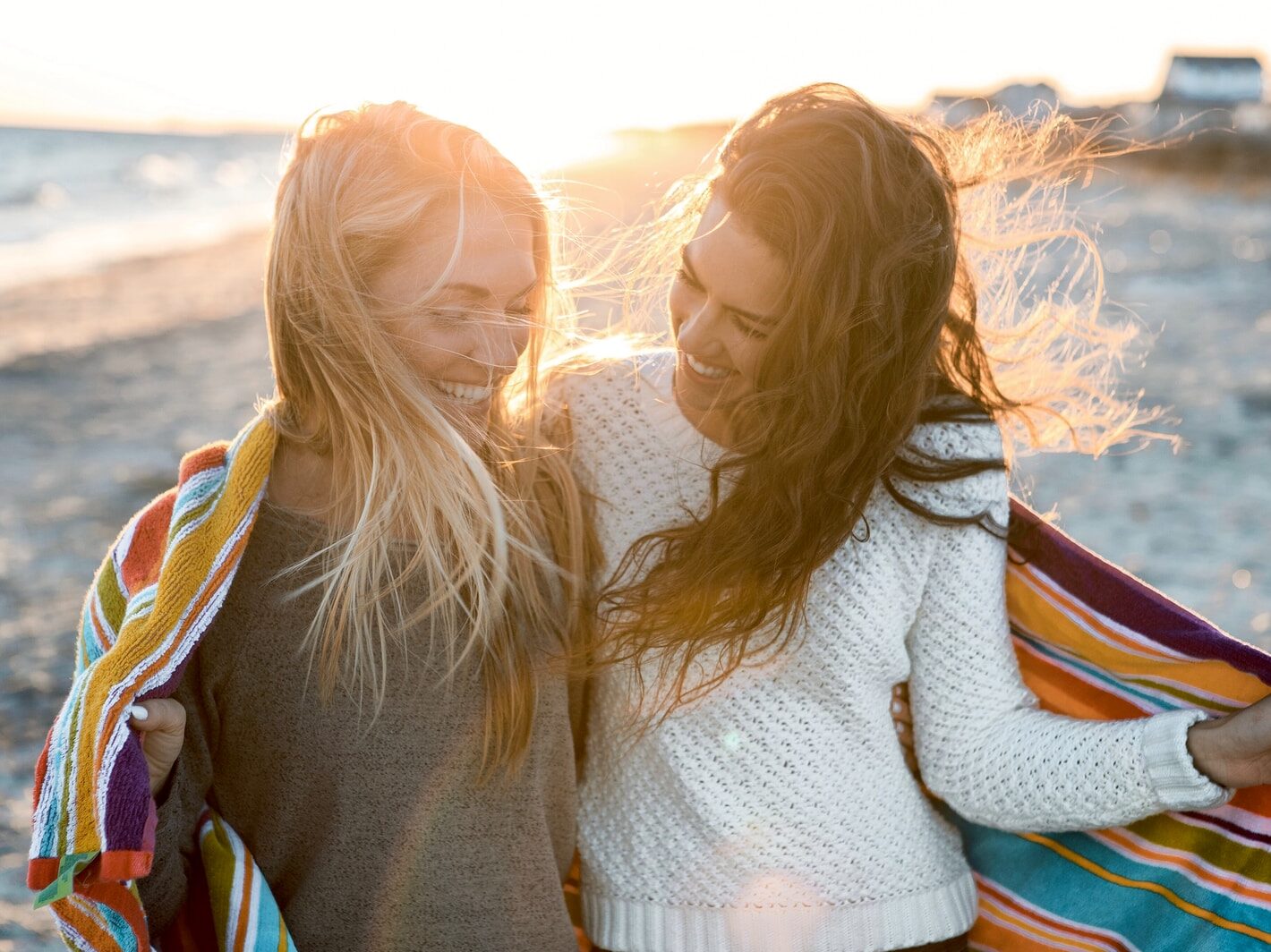 woman wearing gray and white sweater walking on seashore