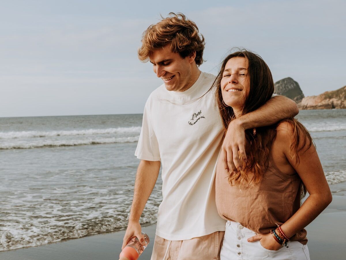 man in white crew neck t-shirt and woman in white t-shirt standing on beach