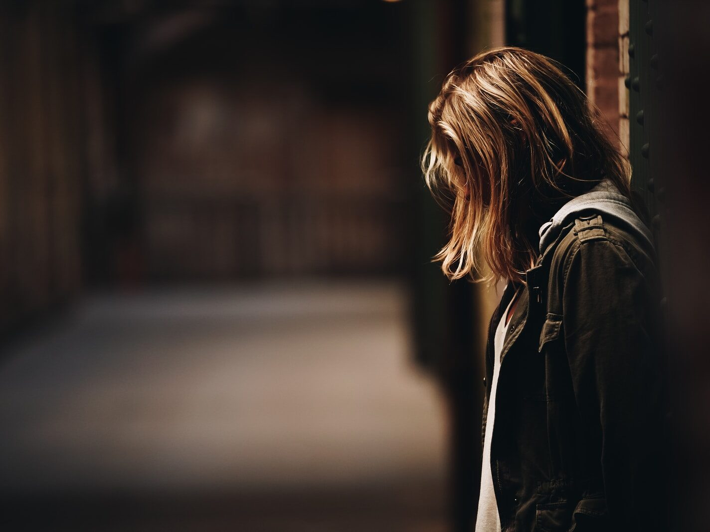 woman leaning against a wall in dim hallway
