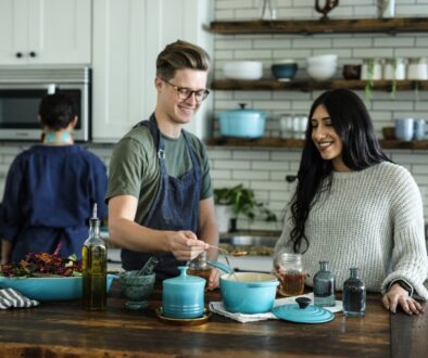 smiling man standing and mixing near woman in kitchen area of the house