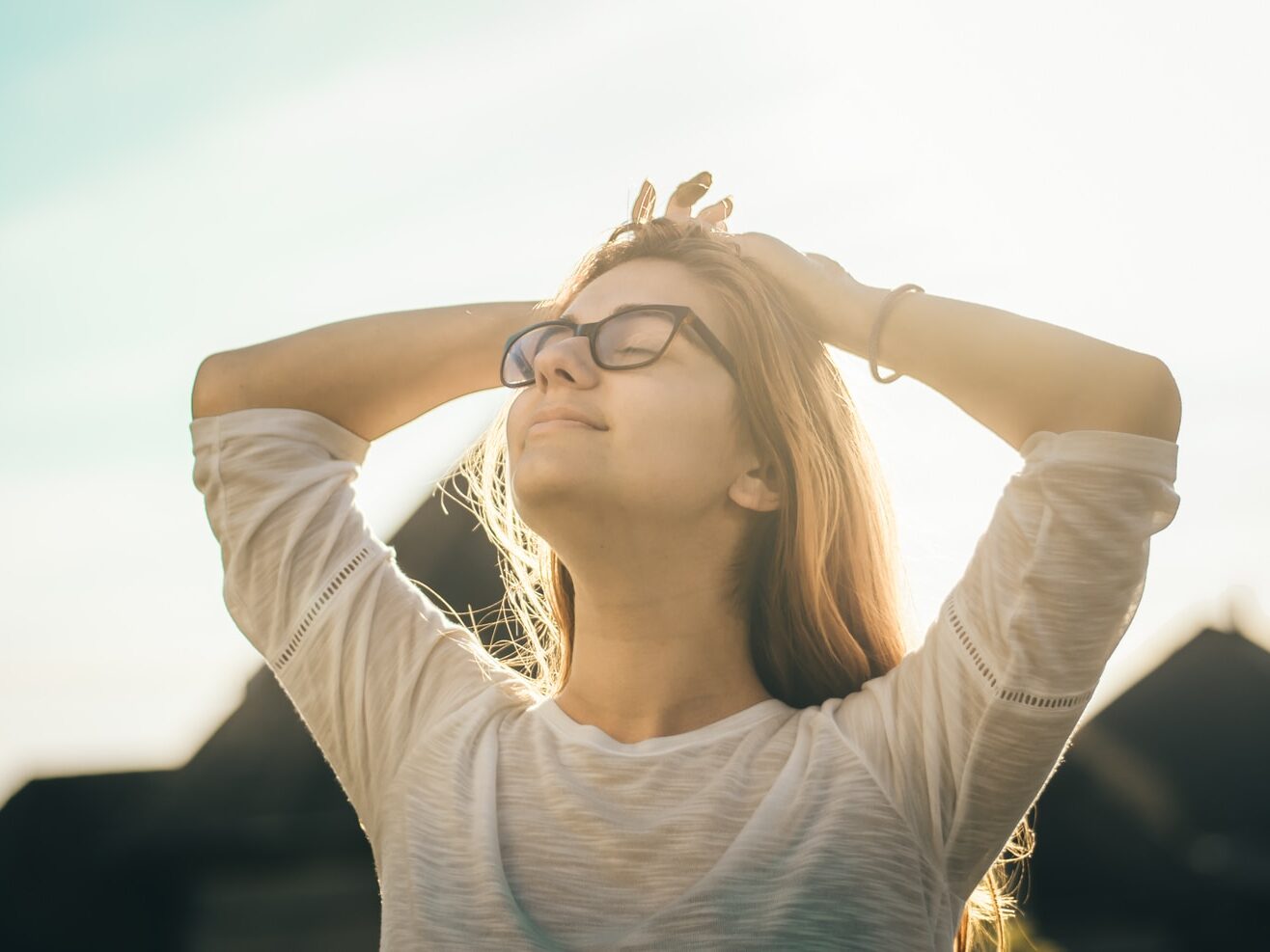 woman in white crew-neck T-shirt holding her head