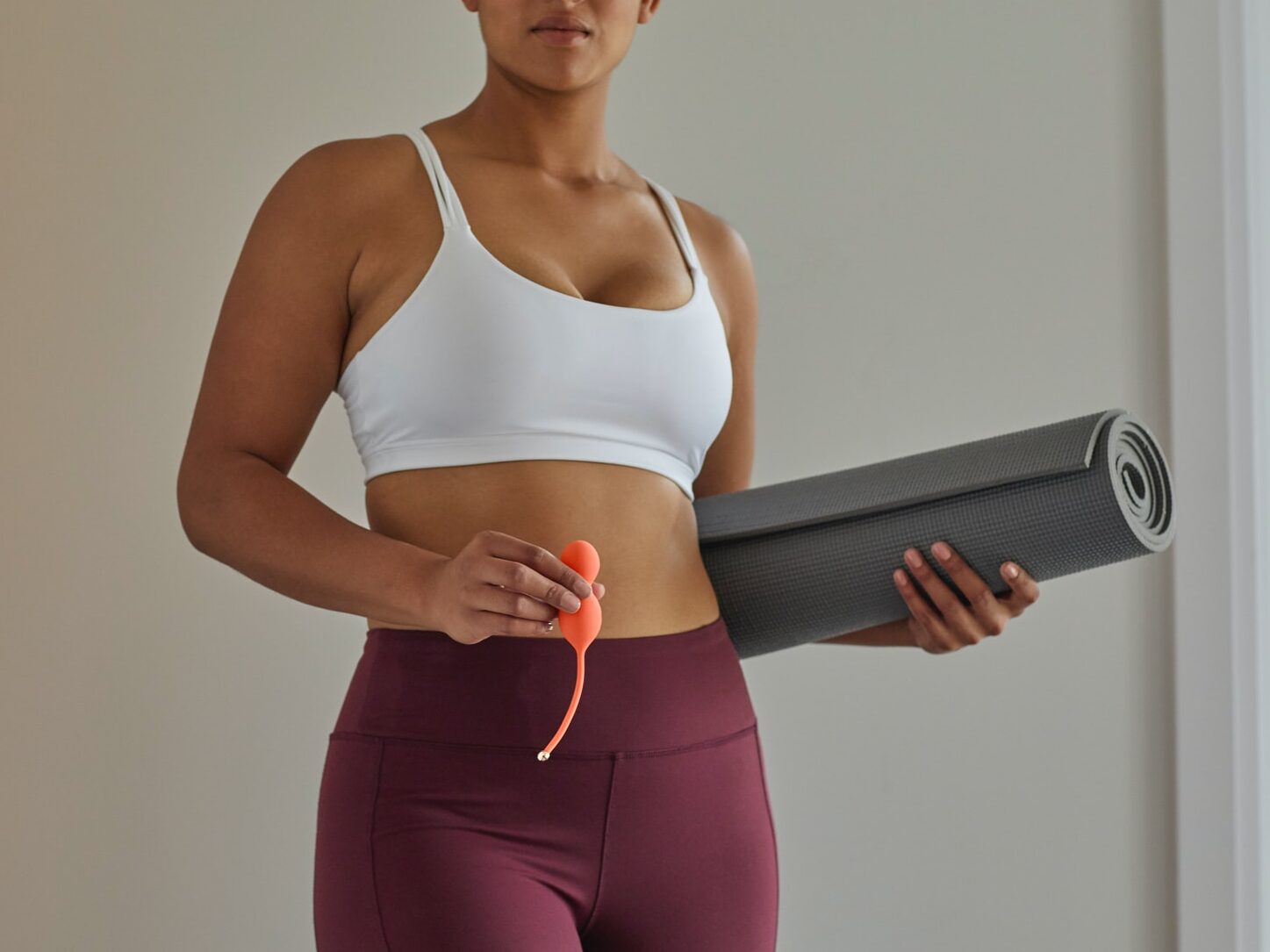 woman in white sports bra and purple leggings holding black speaker