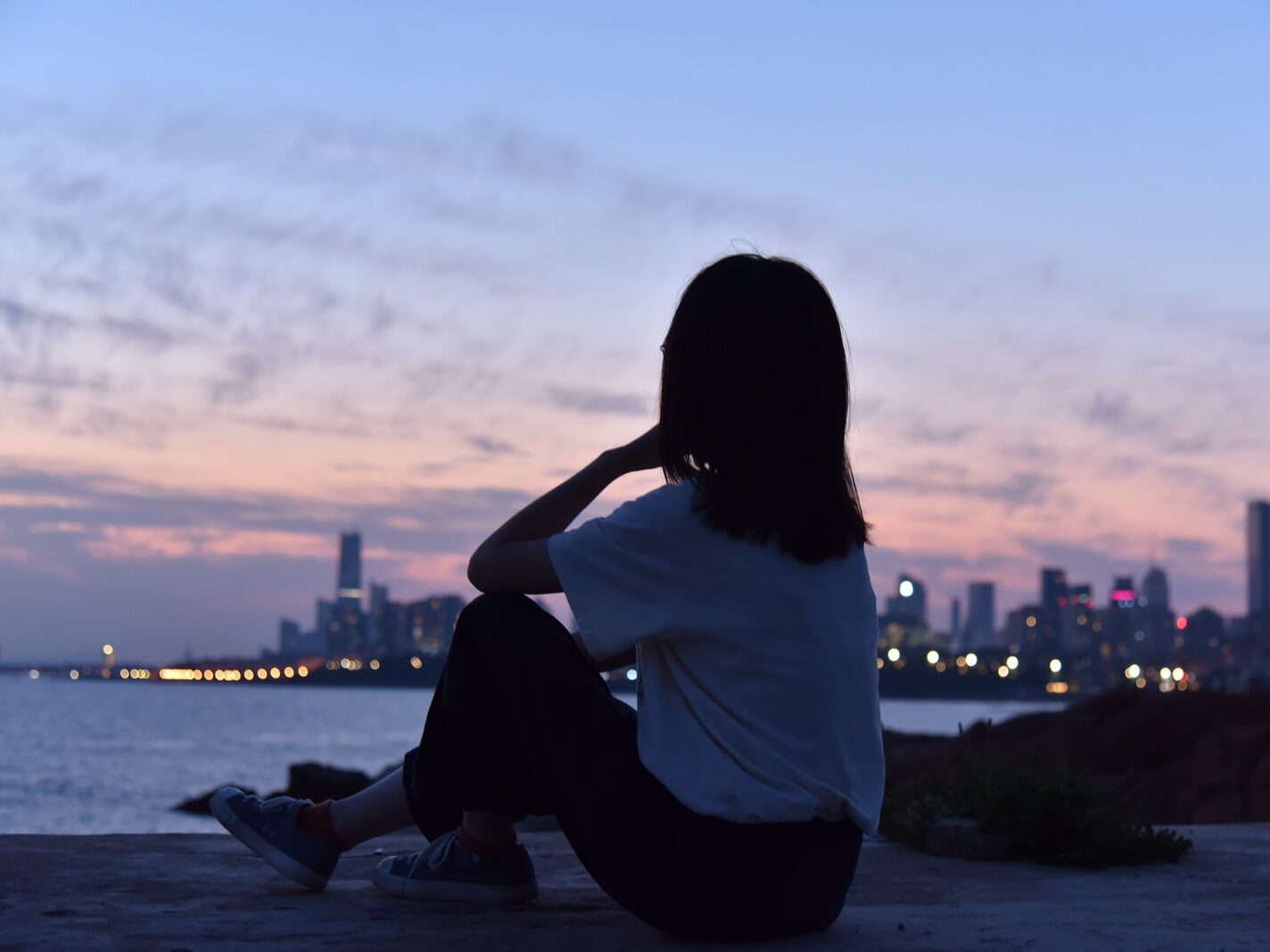 woman in white shirt sitting on the ground during sunset