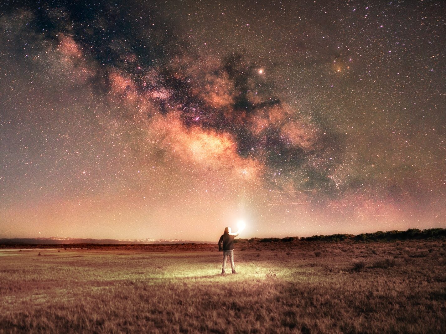 man in white shirt standing on brown grass field under starry night