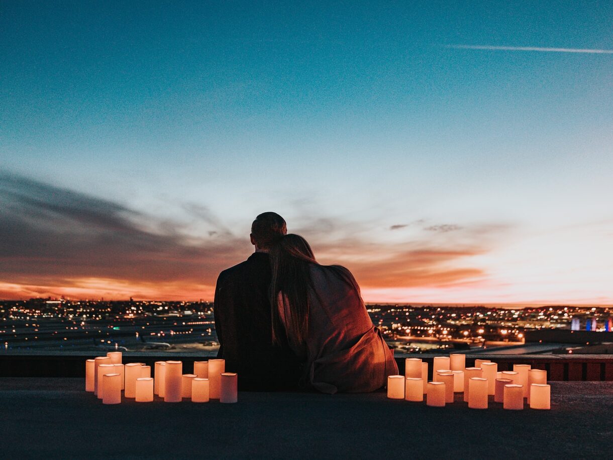 couple sitting on the field facing the city