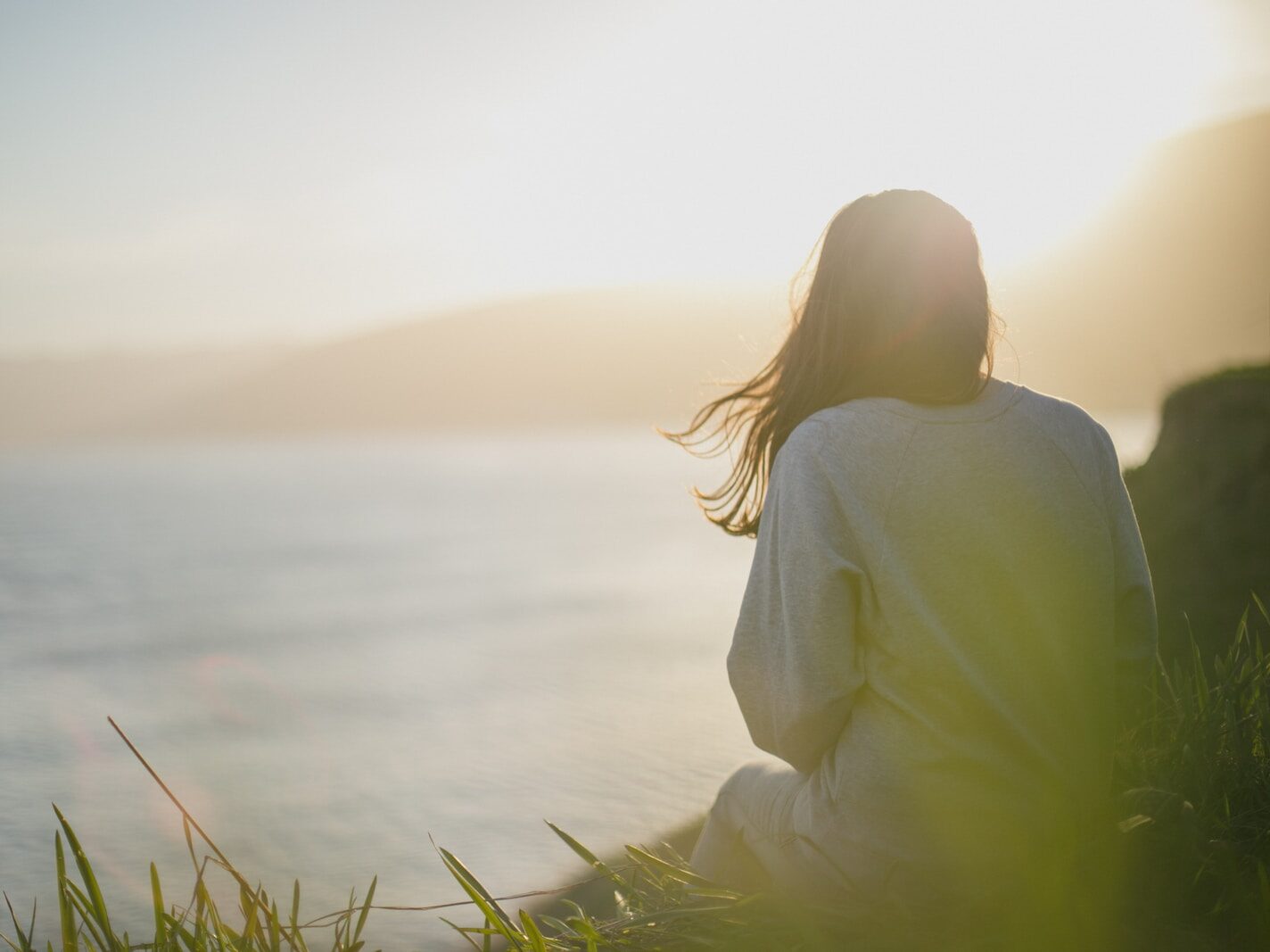woman wearing gray long-sleeved shirt facing the sea