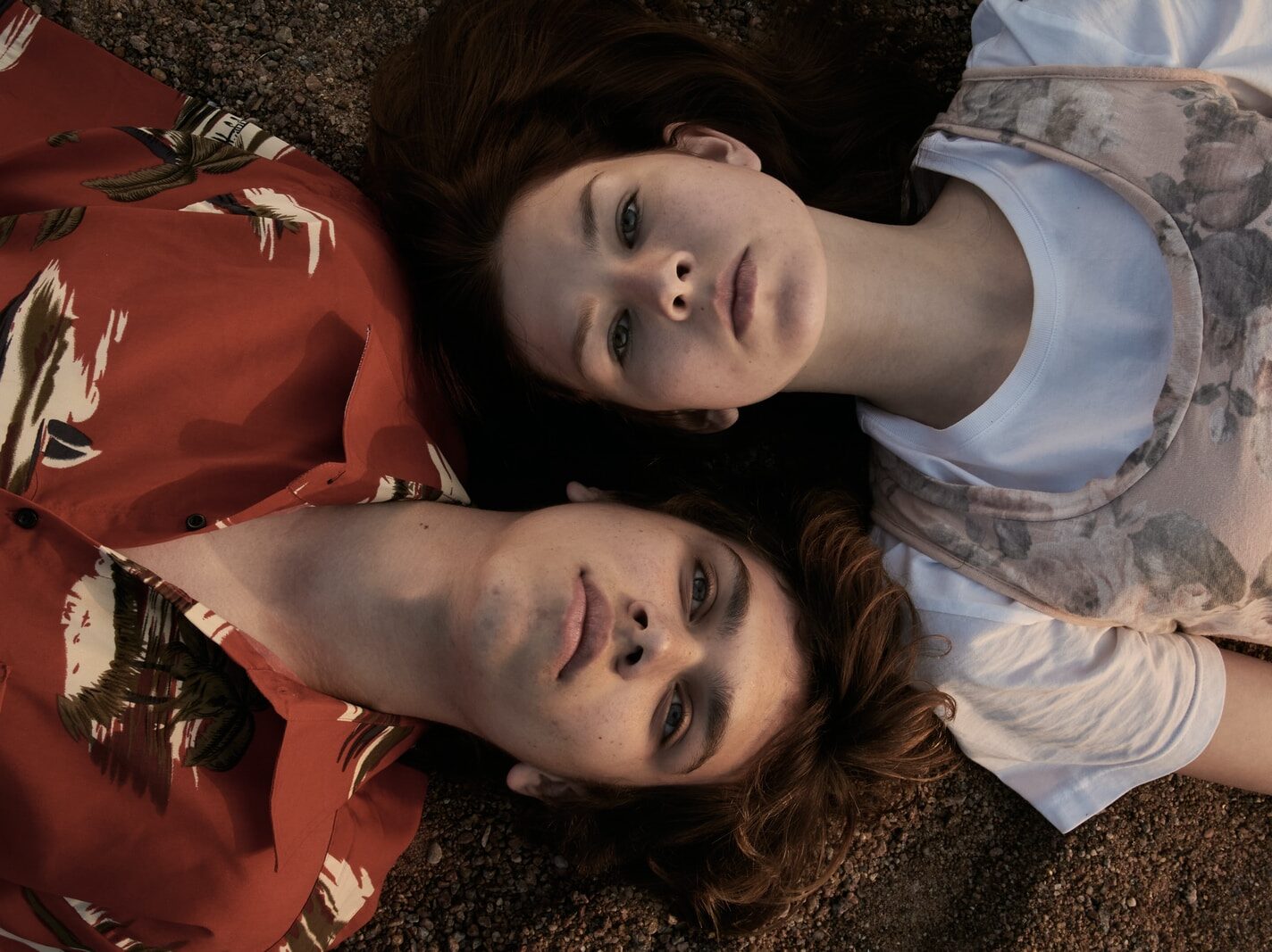 woman in orange and white crew neck shirt lying on brown and black textile