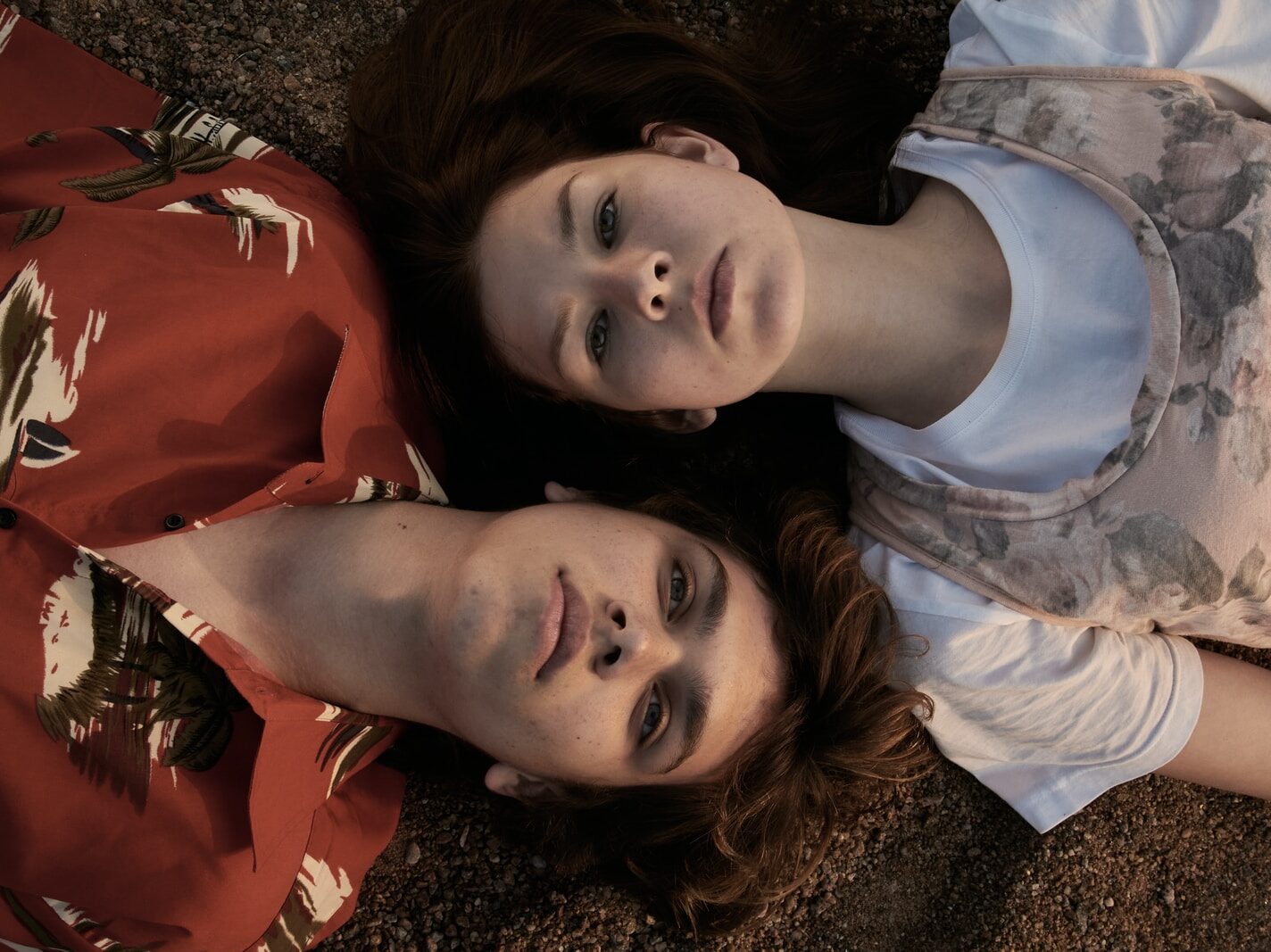 woman in orange and white crew neck shirt lying on brown and black textile