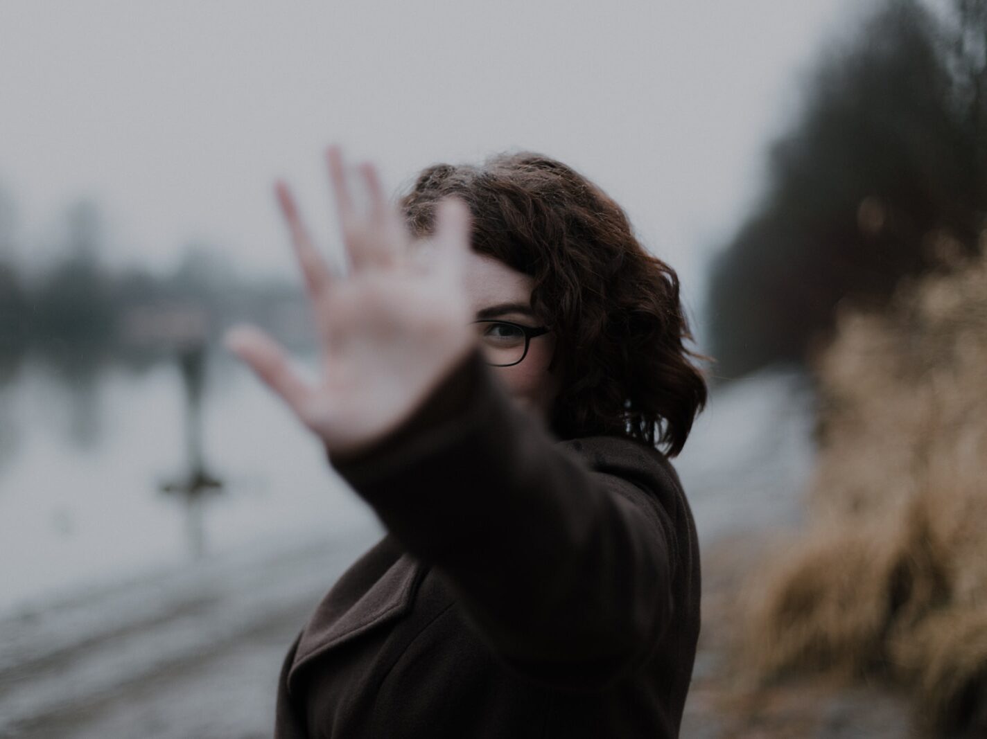 woman in black coat standing near body of water during daytime