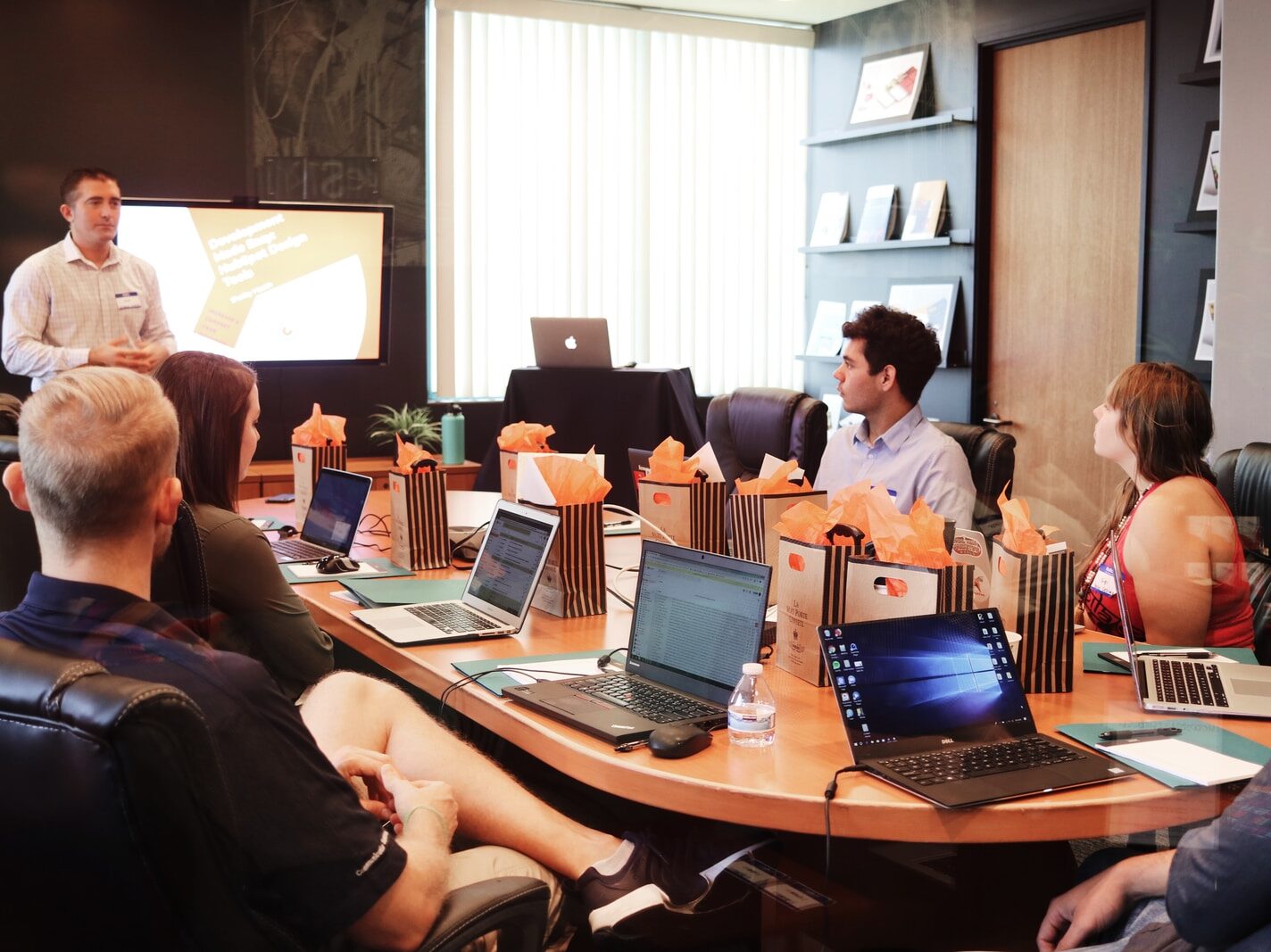 man standing in front of people sitting beside table with laptop computers