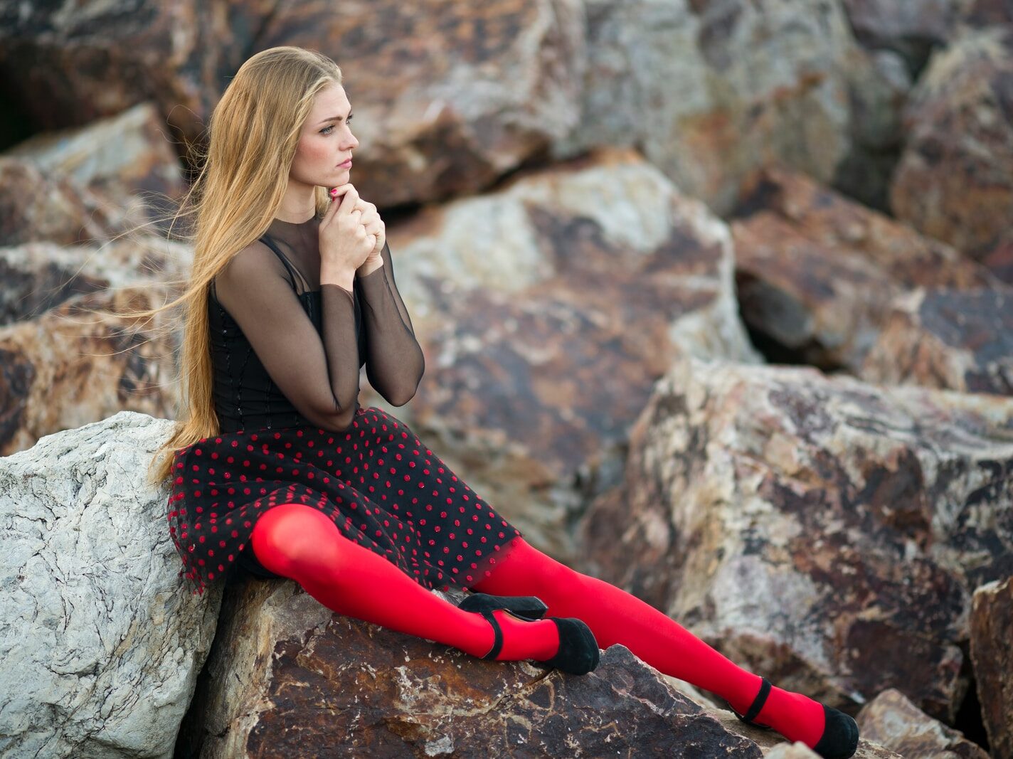 - ČasProŽeny.cz woman in black sleeveless dress sitting on gray rock