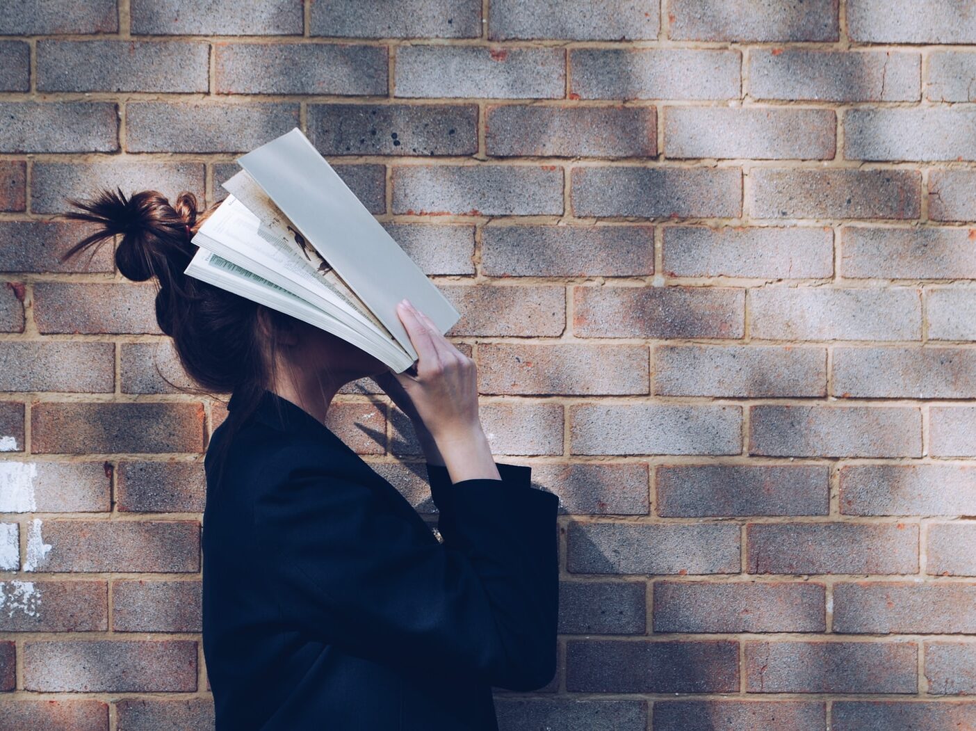 woman covering her face with white book