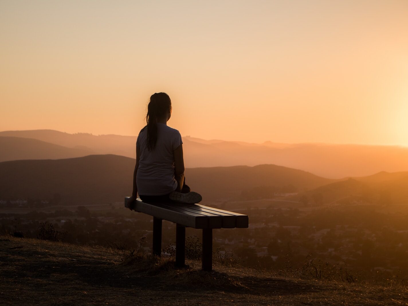 woman sitting on bench over viewing mountain