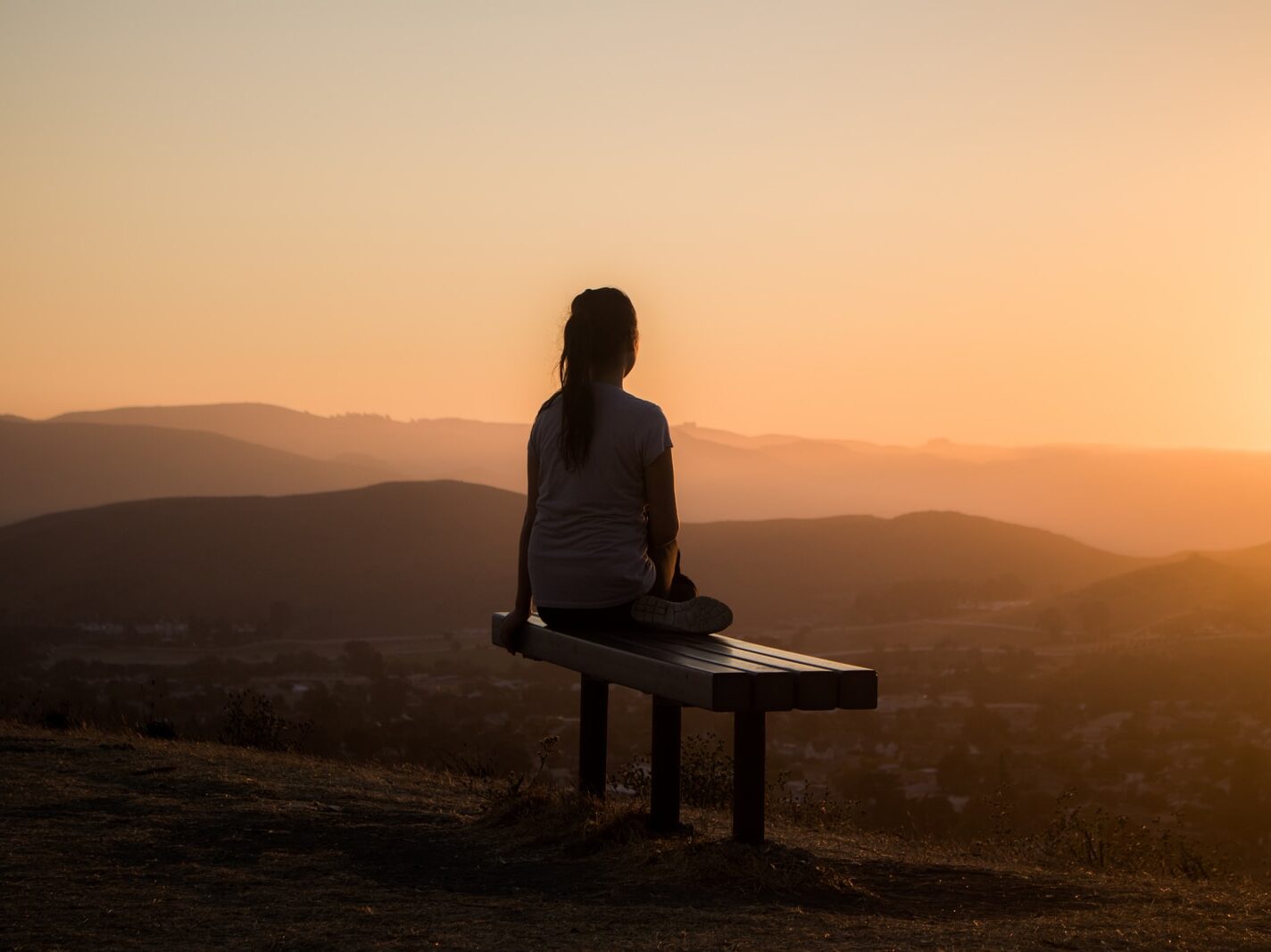 woman sitting on bench over viewing mountain