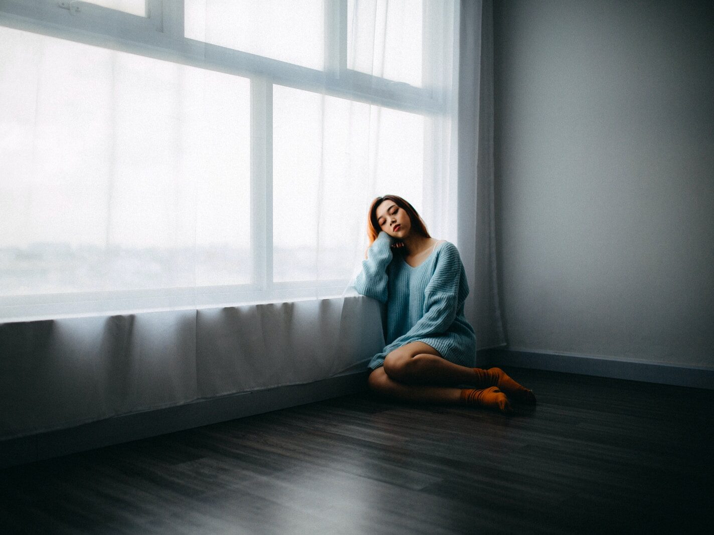 woman sitting on floor near window